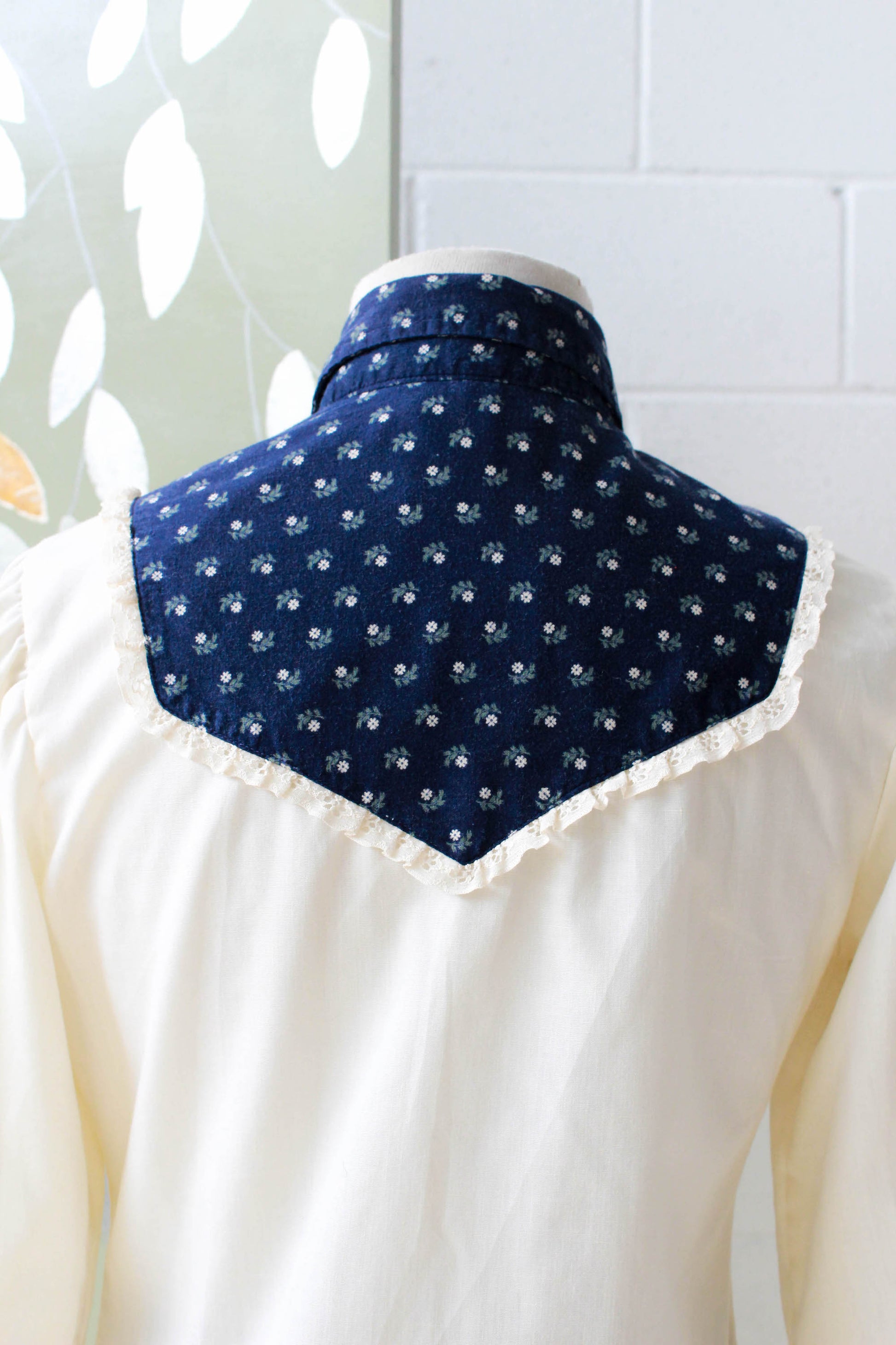 1970s vintage coastal cowgirl style cream prairie blouse with puff sleeves and navy blue floral yoke with collar, long sleeves and snap front