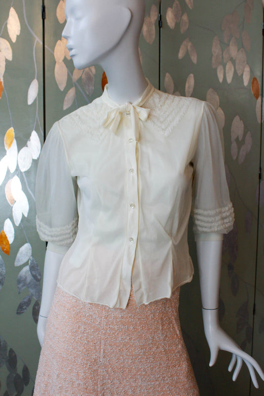 1950s nylon chiffon cream blouse with puff sleeves and faux ruffle appliqued collar design with tie neckline, sheer puff sleeves and clear rhinestone buttons vintage coquette aesthetic romantic feminine blouse