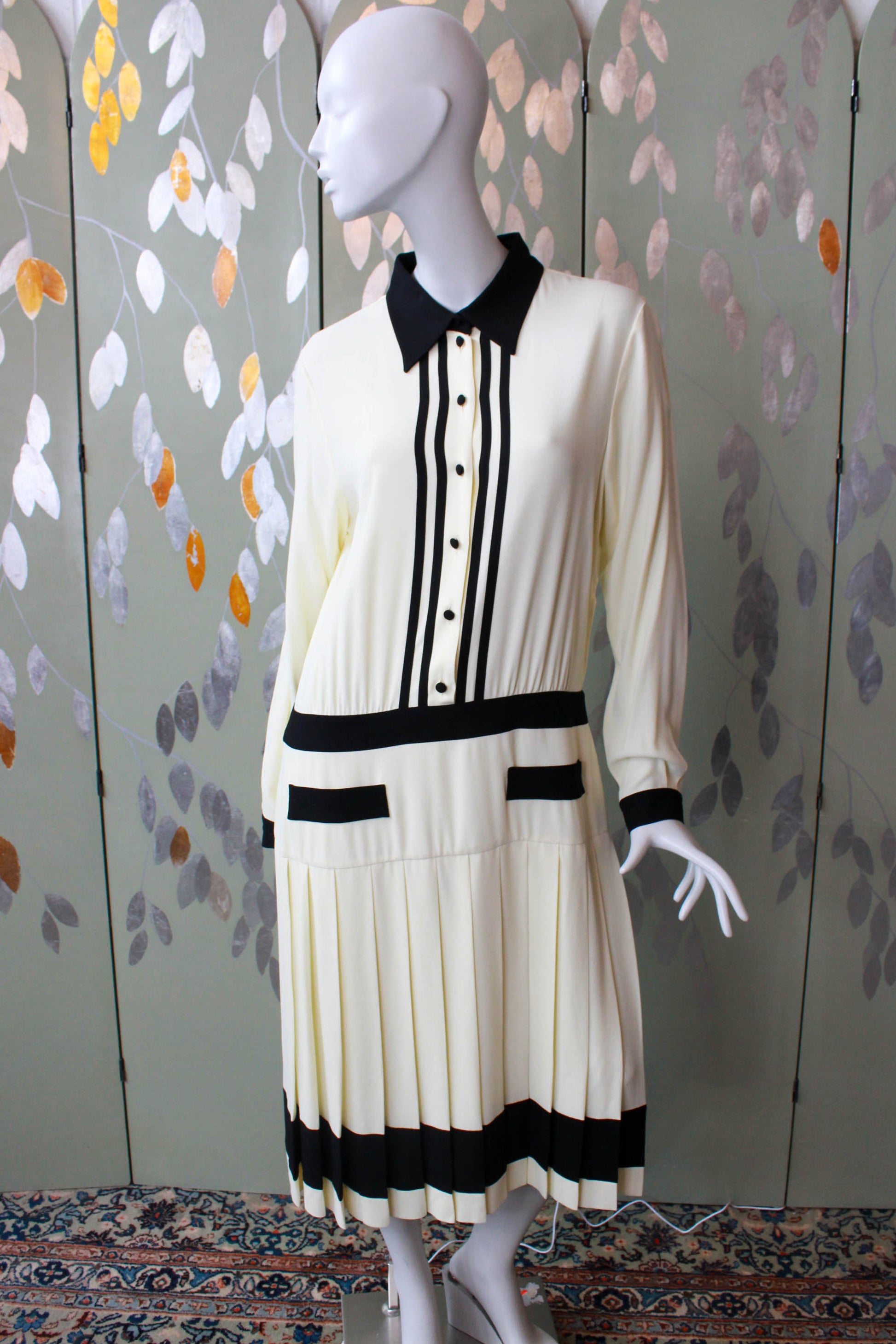y2k Moschino 1920s style drop waist shirt dress, button up with collar, cream with black contrast bands at waist, pockets, hem, cuffs collar. Pleated skirt, faux pockets