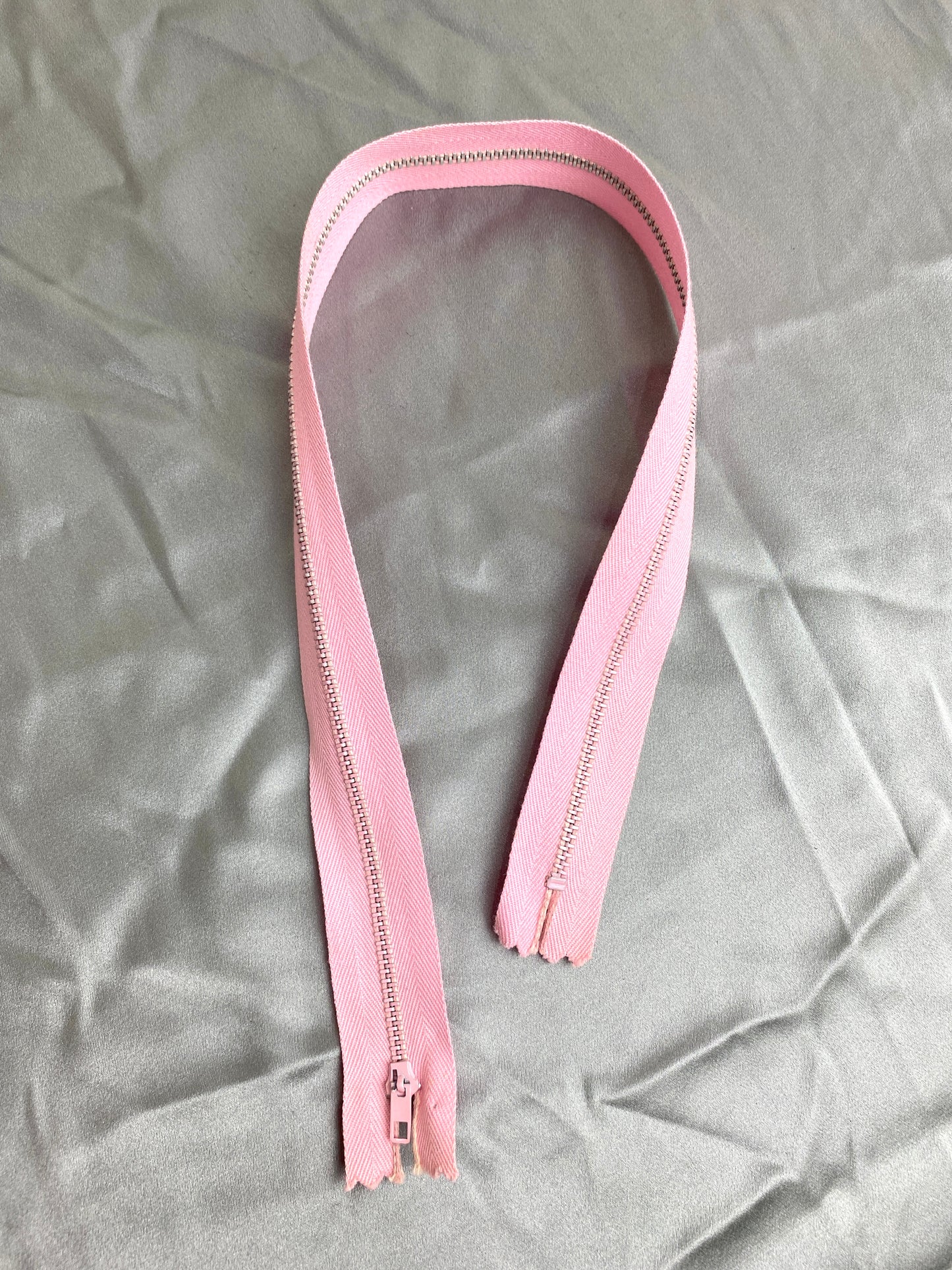 A single vintage pink metal zipper. Ian Drummond Vintage.