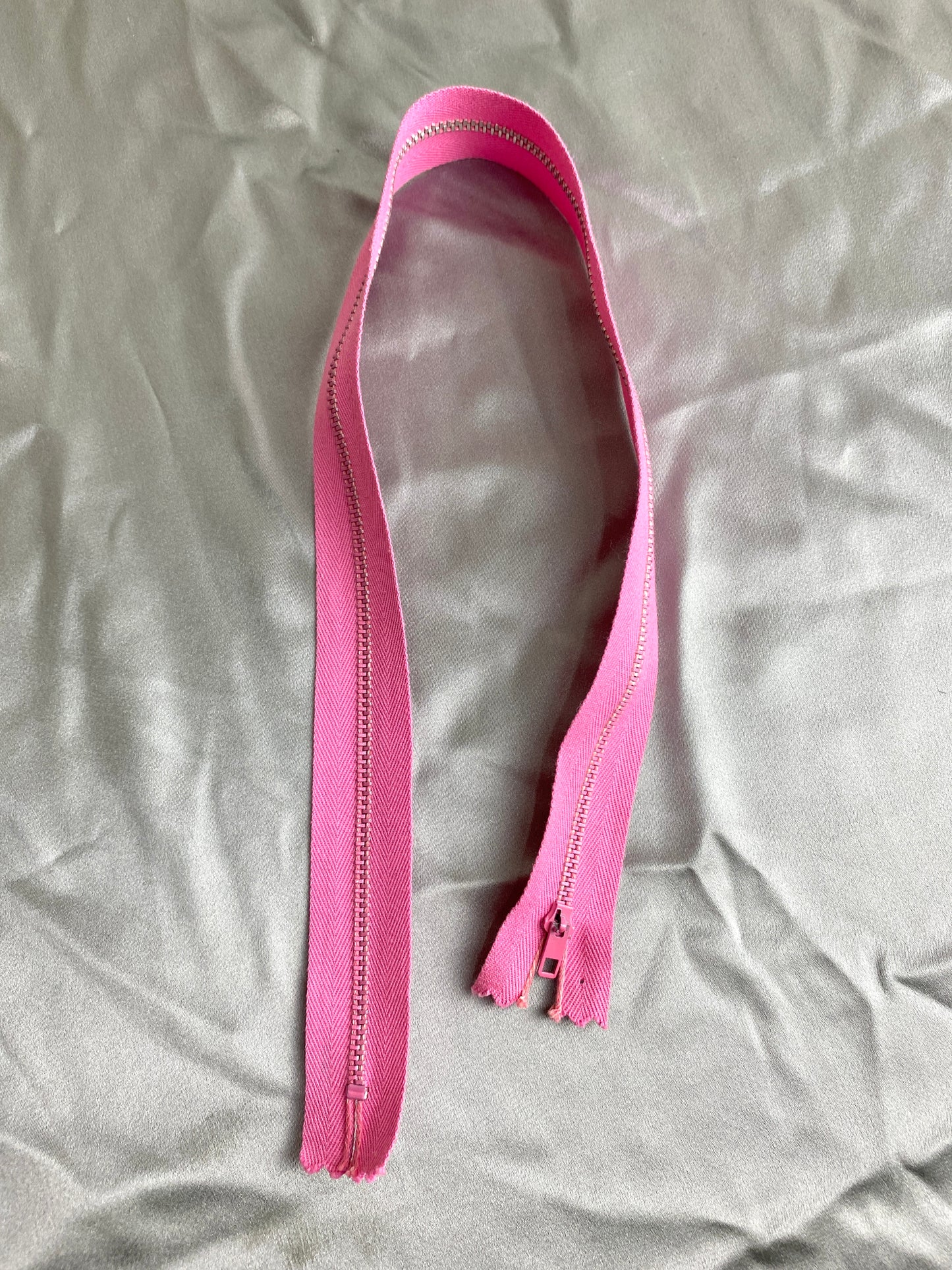 A single pink metal vintage zipper. Ian Drummond Vintage.