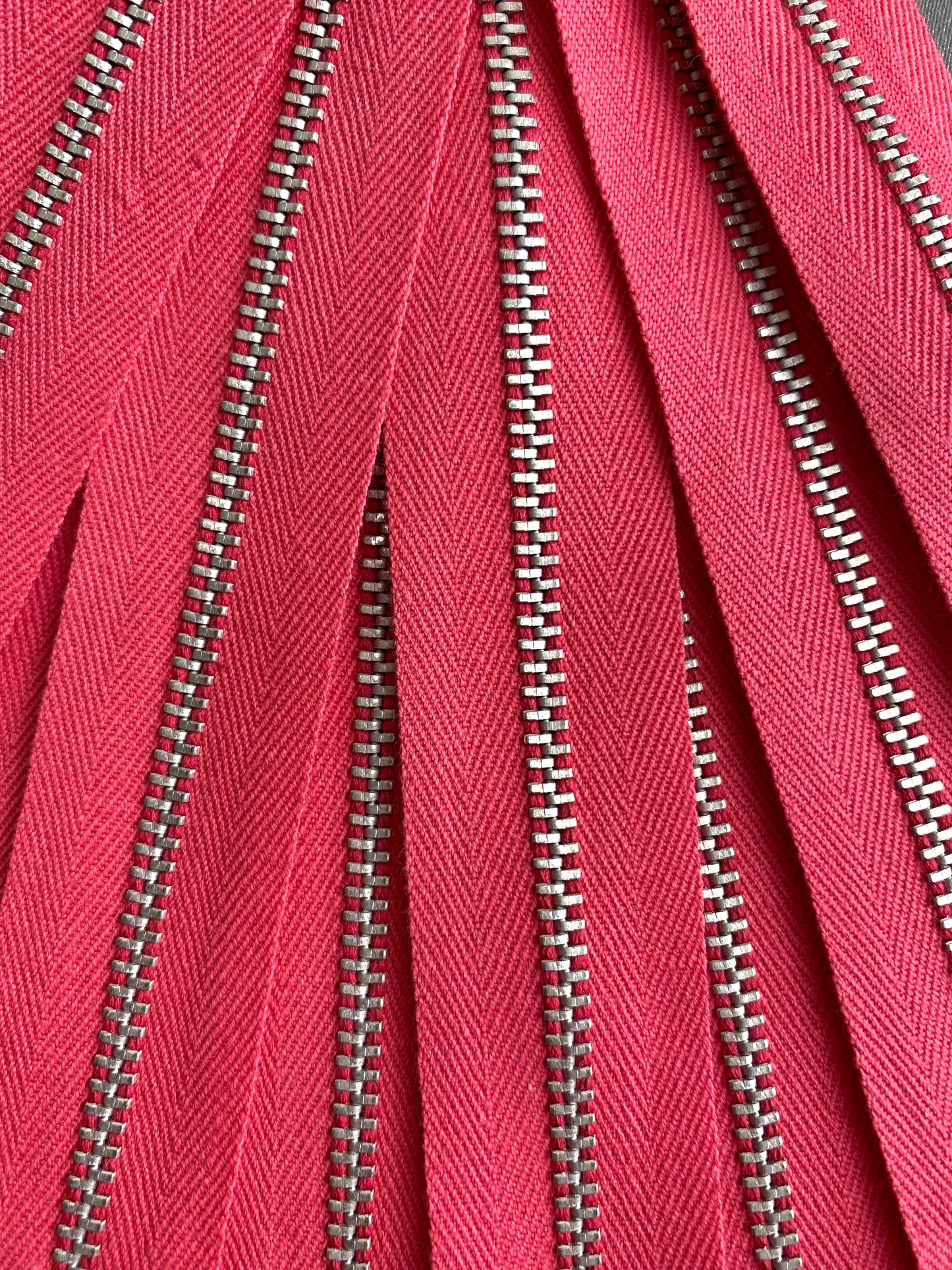 A close-up of a batch of pink metal zippers. Ian Drummond Vintage.