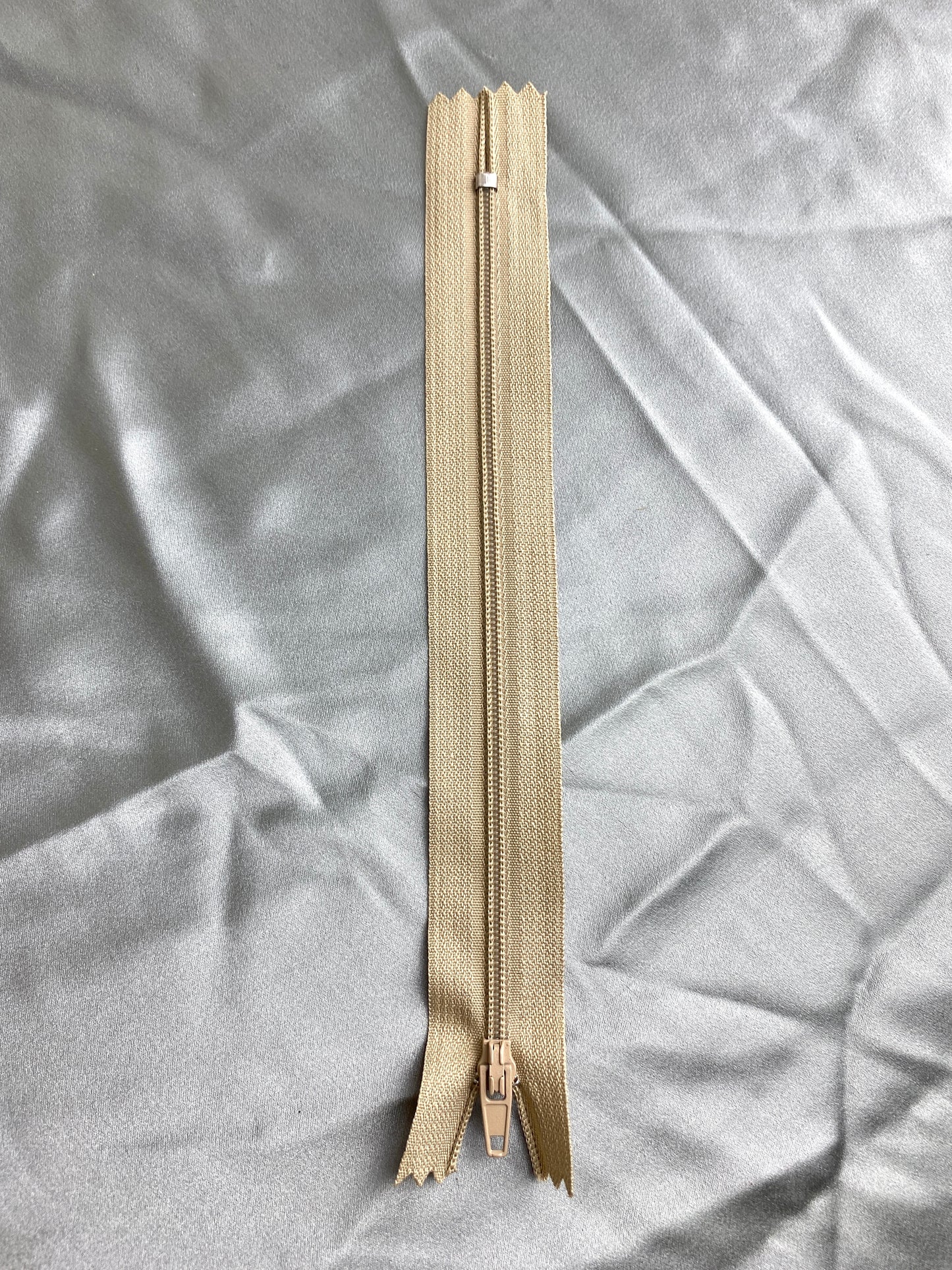 A single plastic tan zipper. Ian Drummond Vintage.