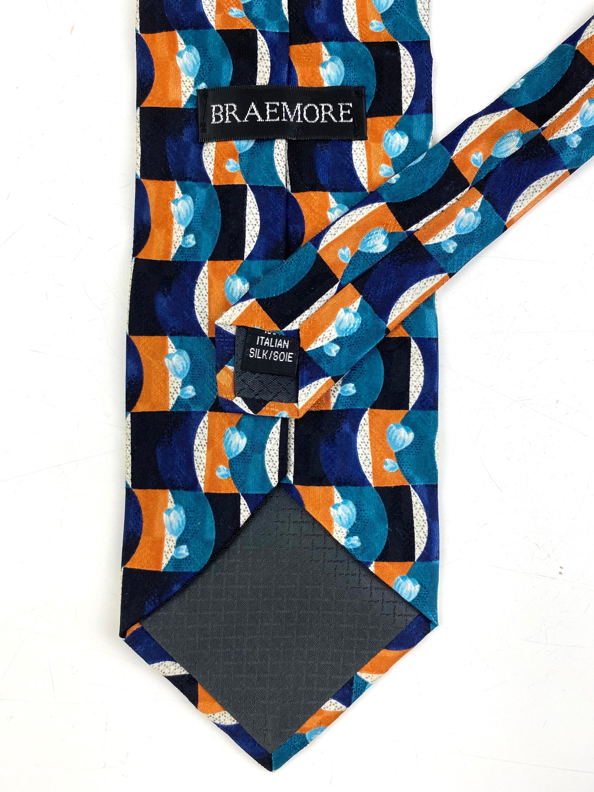 Back and labels of: 90s Deadstock Silk Necktie, Men's Vintage Teal/ Purple/ Orange Geometric Pattern Tie, NOS