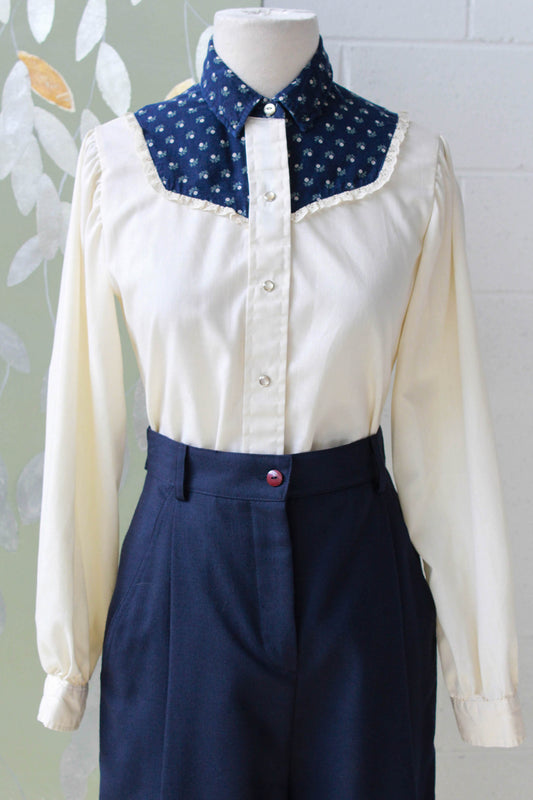 1970s vintage coastal cowgirl style cream prairie blouse with puff sleeves and navy blue floral yoke with collar, long sleeves and snap front