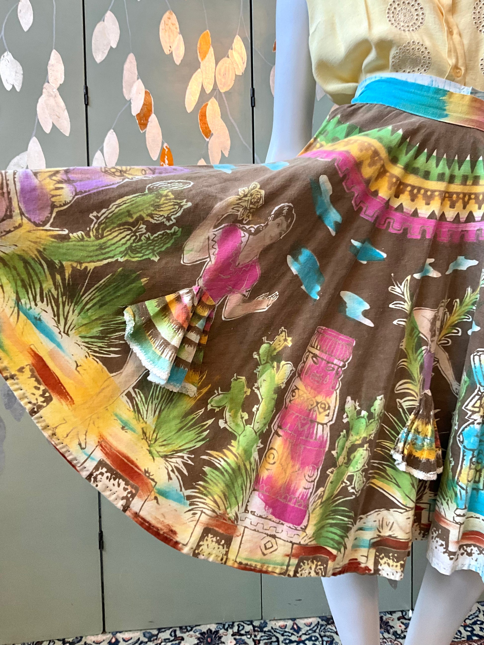 Colorful skirt with a Mexican design featuring people, plants, and statues.