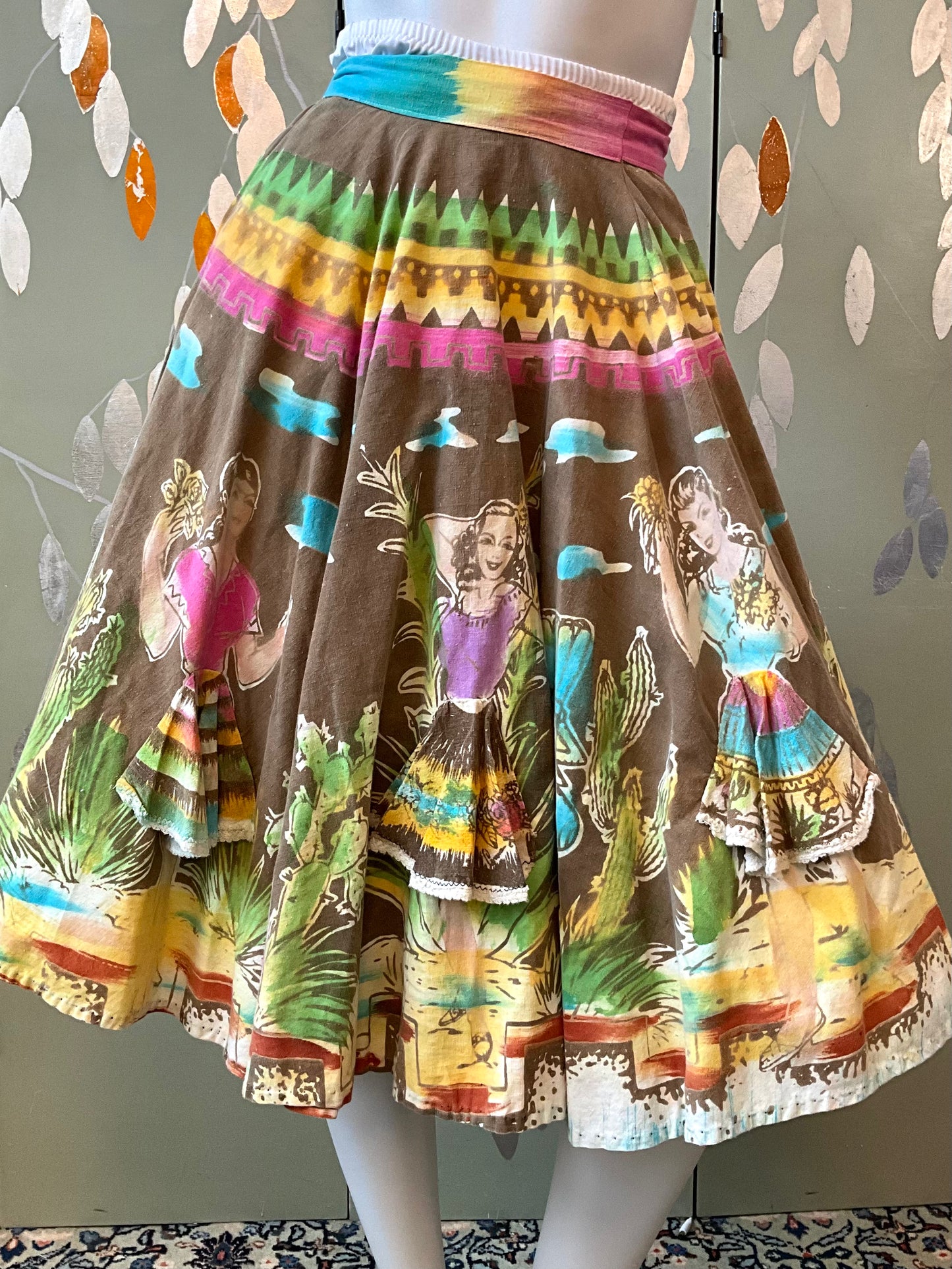 Skirt with colorful print on a mannequin against a patterned wall.