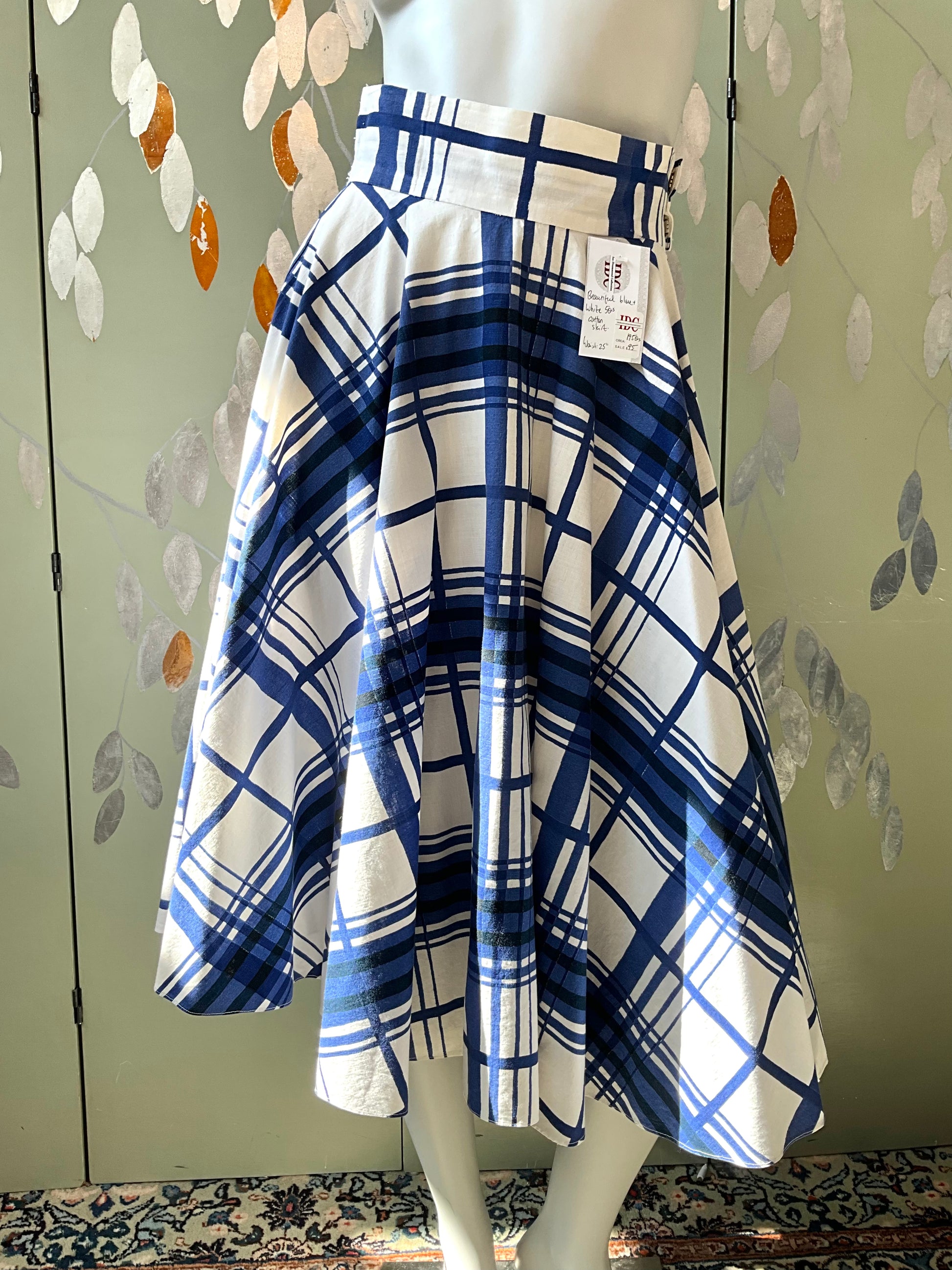 Blue and white plaid skirt on a mannequin against a patterned wall.