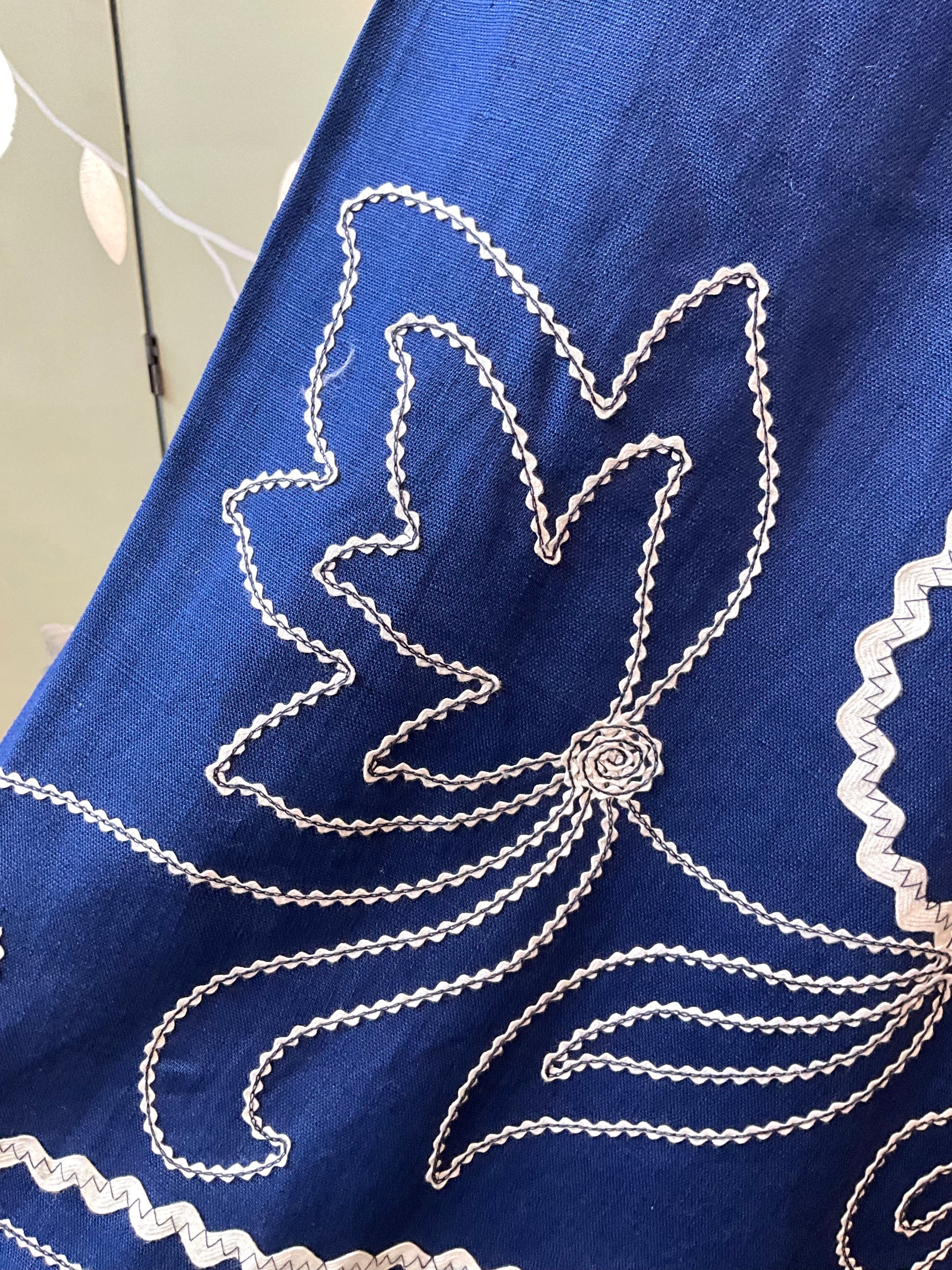 Blue fabric with white embroidery of a floral design.