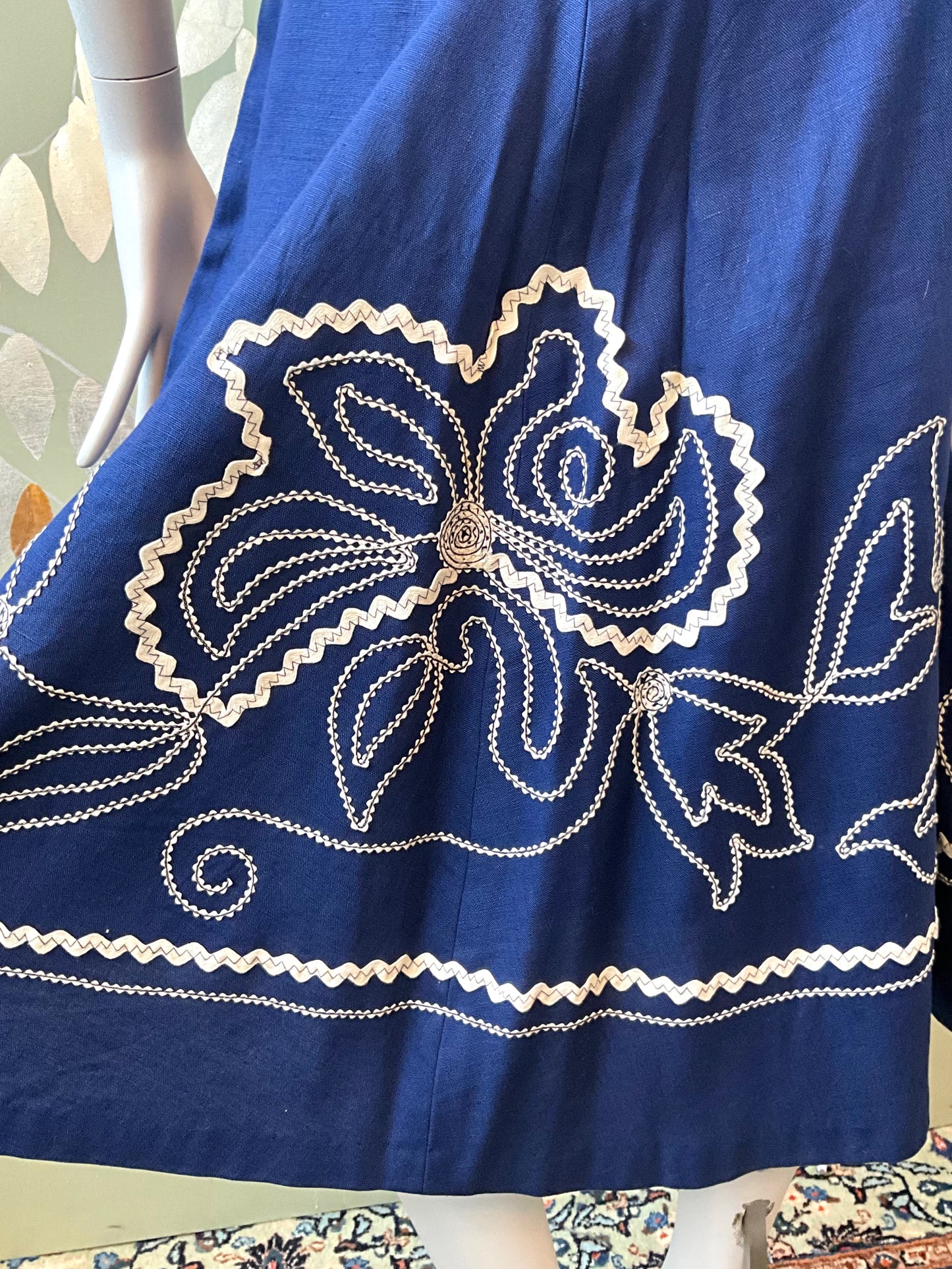 Blue fabric with white floral embroidery on a mannequin.