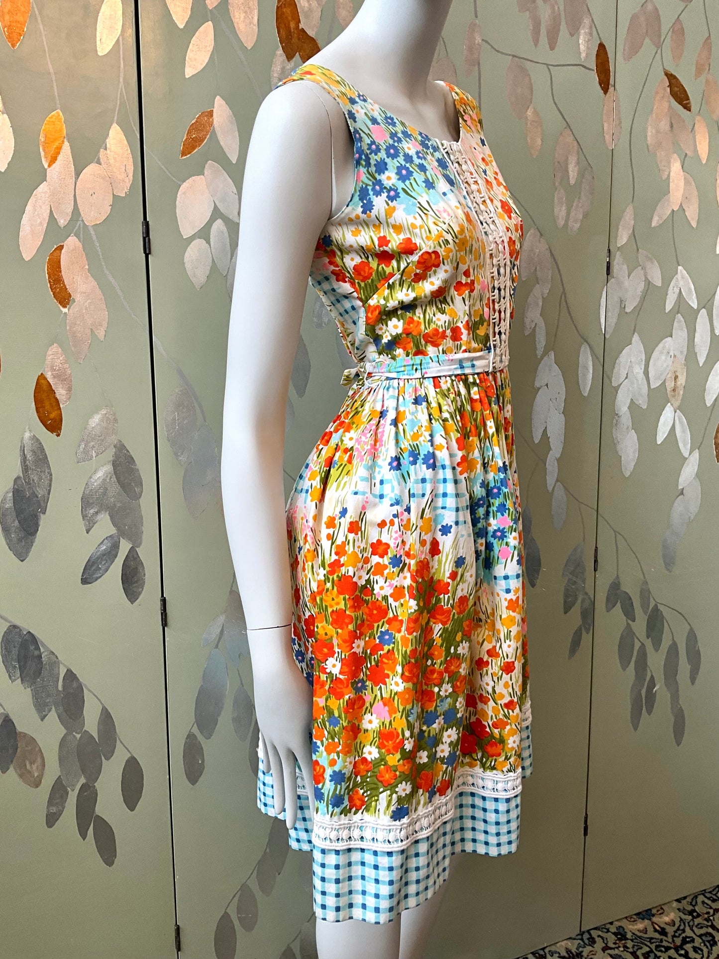 Mannequin wearing a colorful floral dress against a decorative wall.