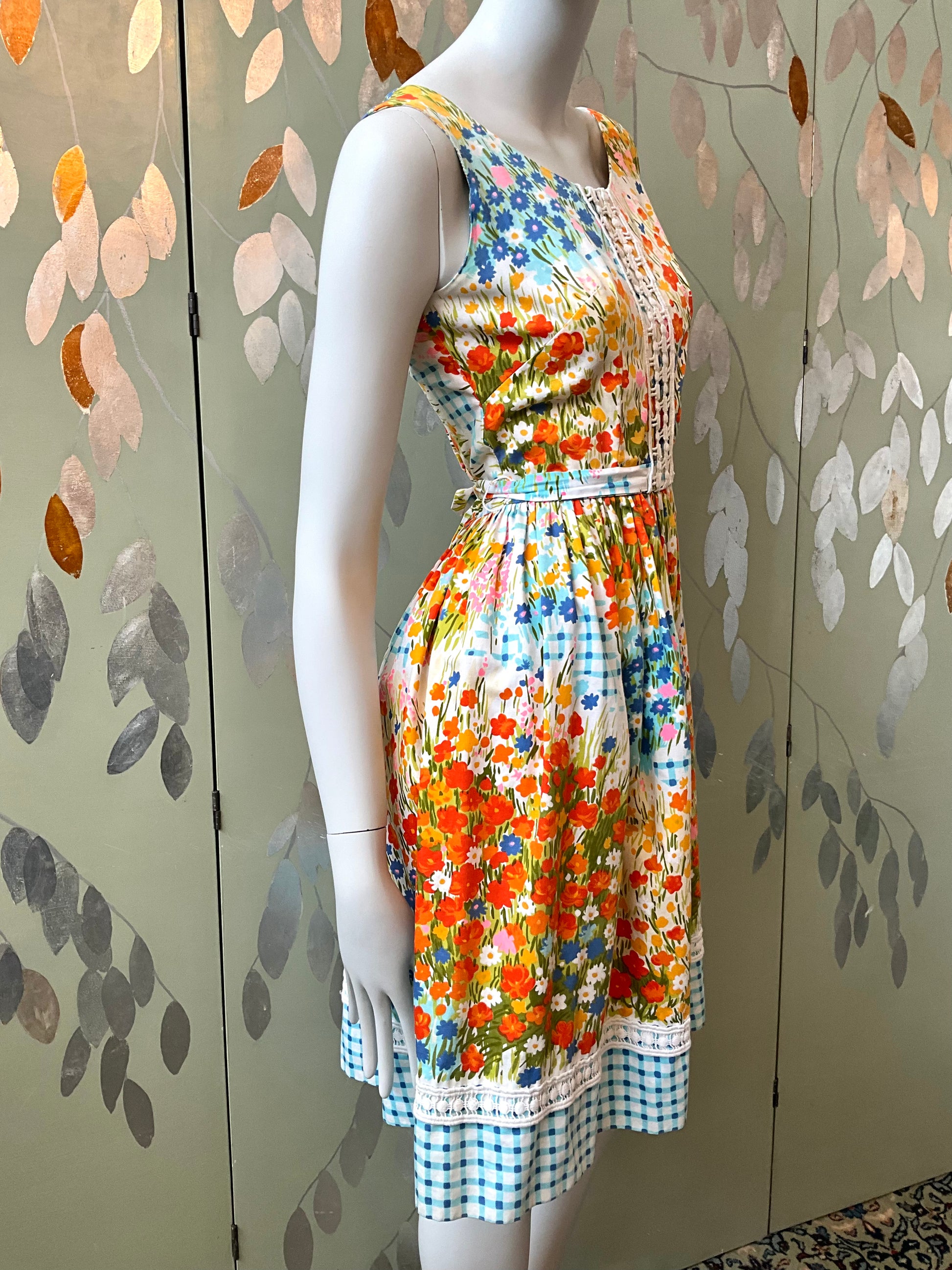 Mannequin wearing a colorful floral dress against a decorative wall.