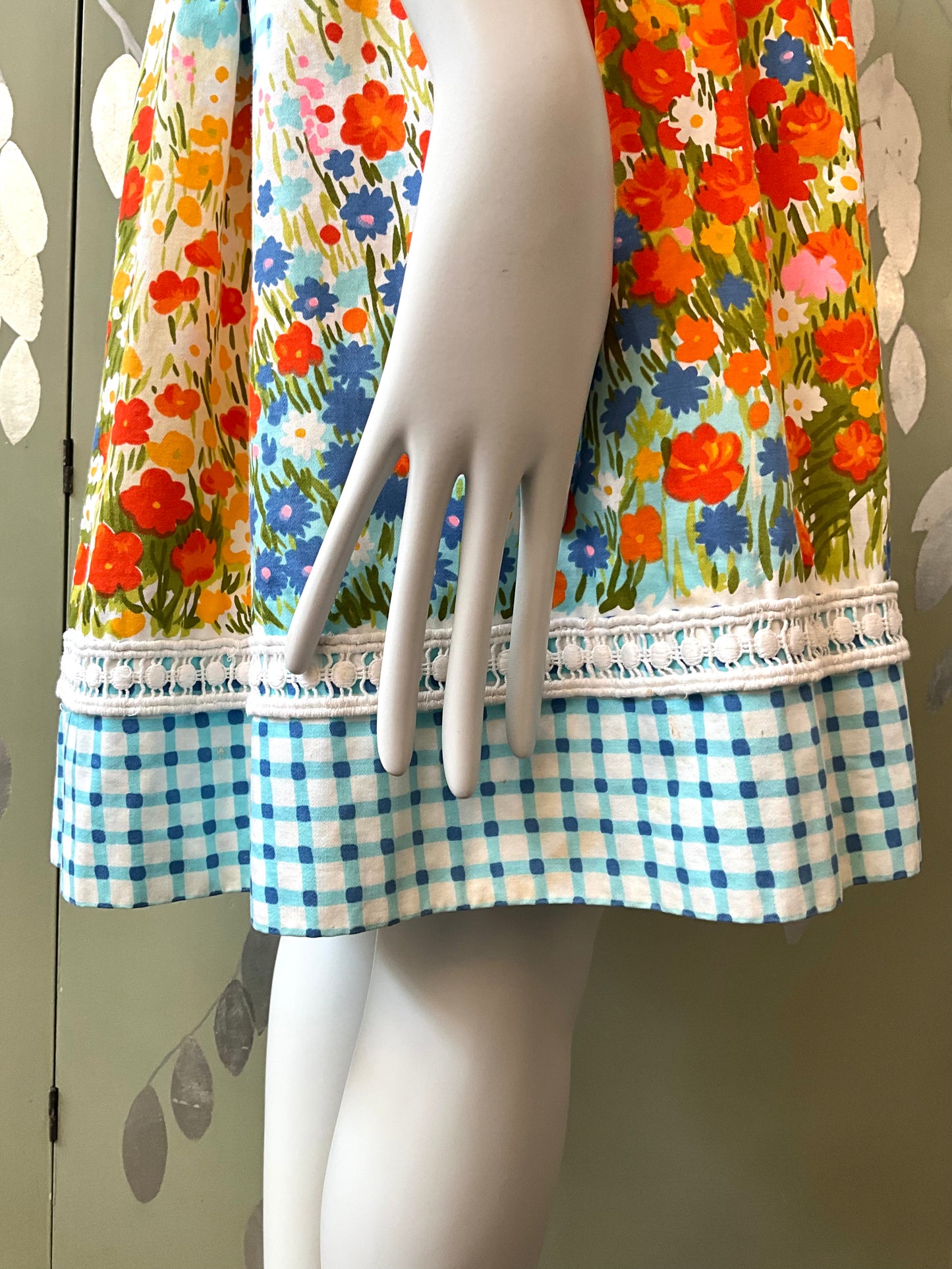 Mannequin wearing a colorful floral dress with a checkered bottom section against a neutral background