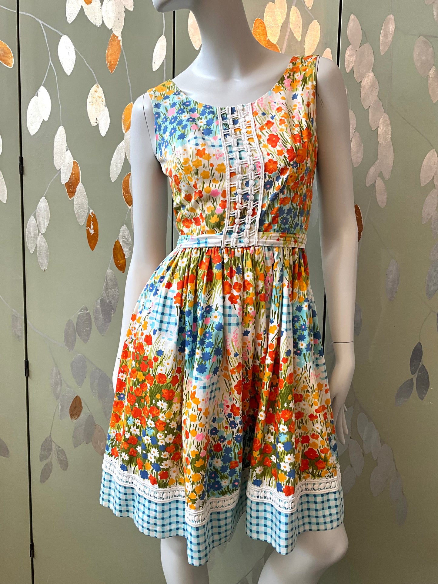 Colorful floral dress on a mannequin against a patterned wall.