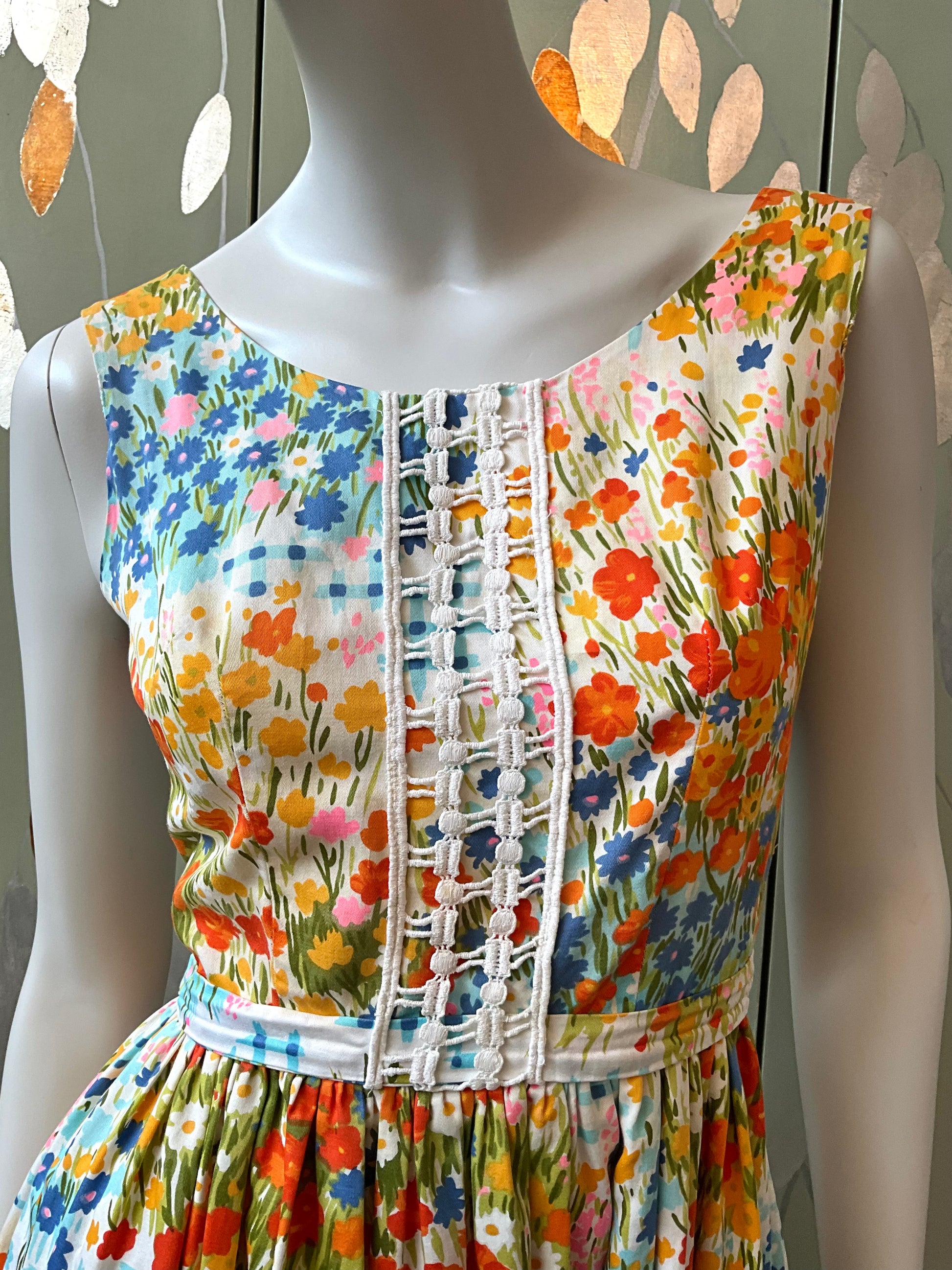 Mannequin wearing a colorful floral dress with a patterned bodice against a neutral background.