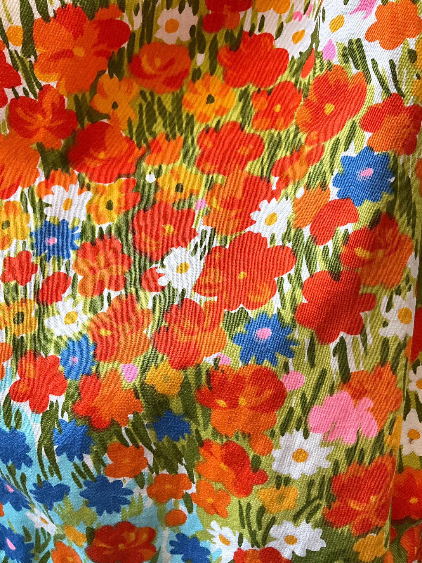 Colorful floral pattern with red, orange, blue, and pink flowers on a green background.