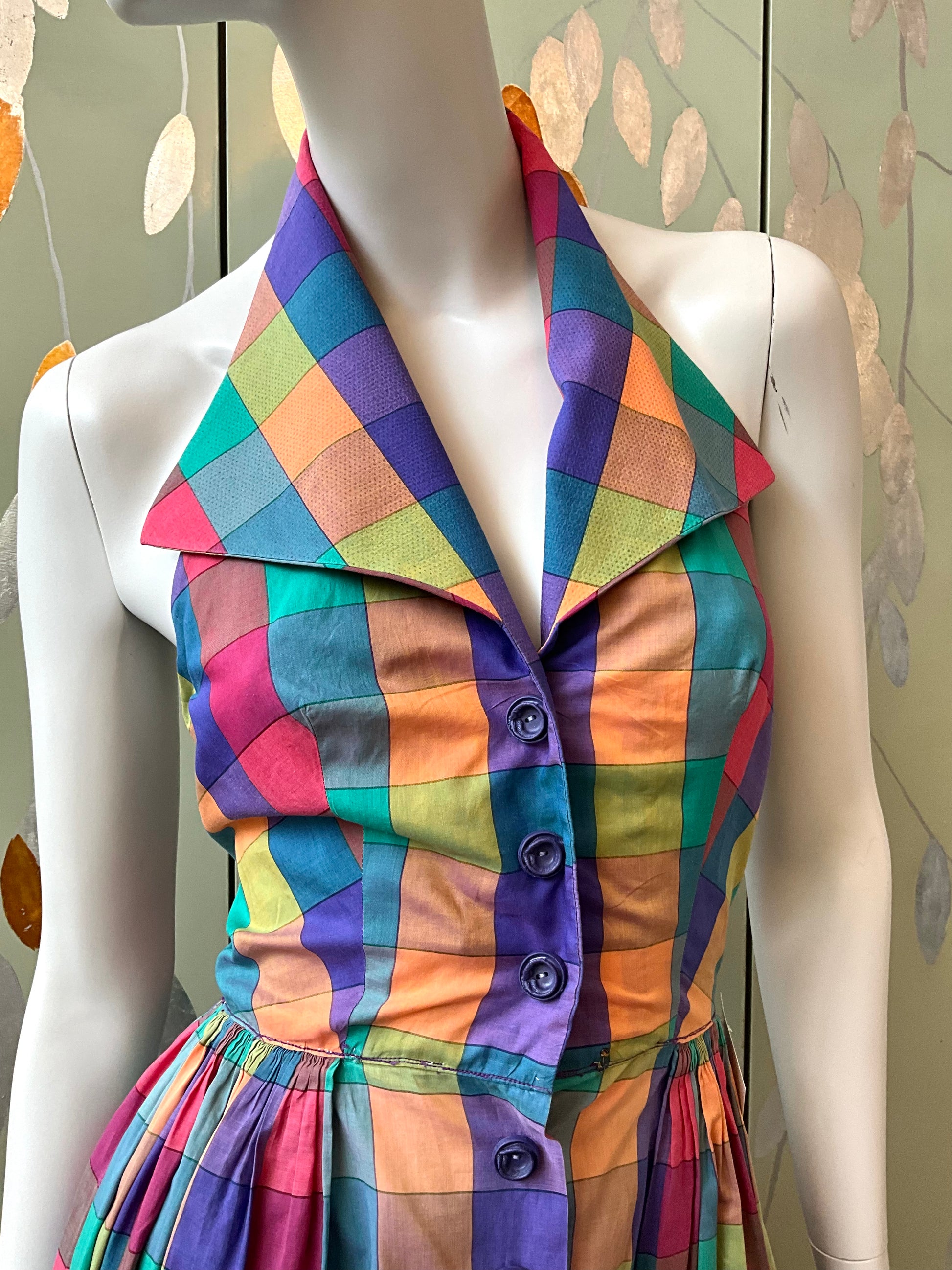 Mannequin wearing a colorful checkered dress with a patterned background