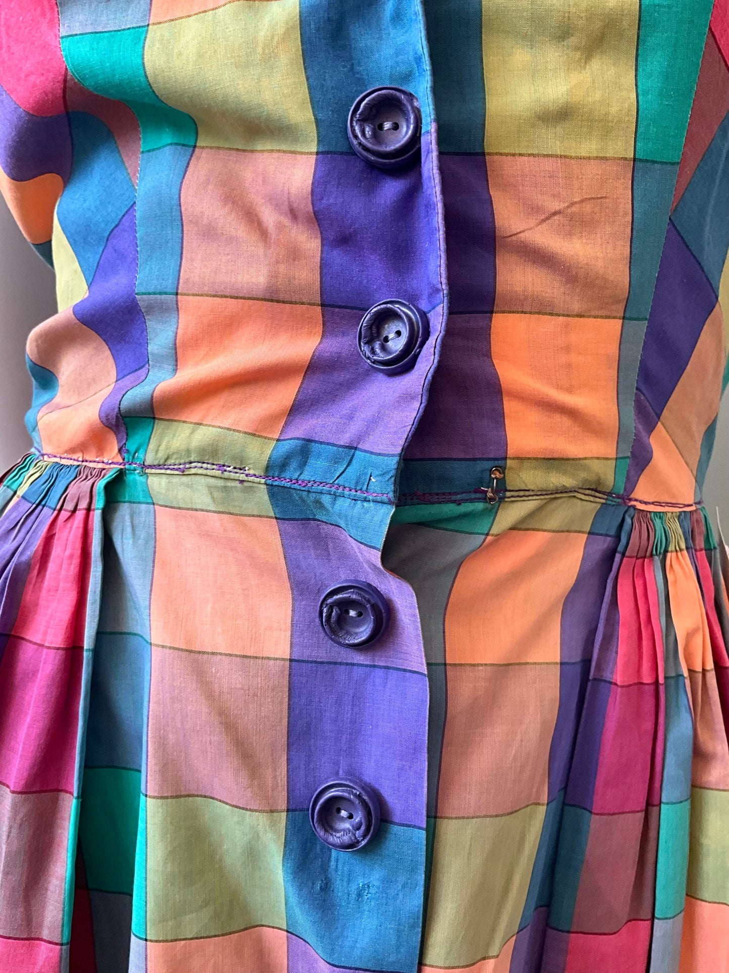 Multicolored checkered fabric with three buttons on a plain background