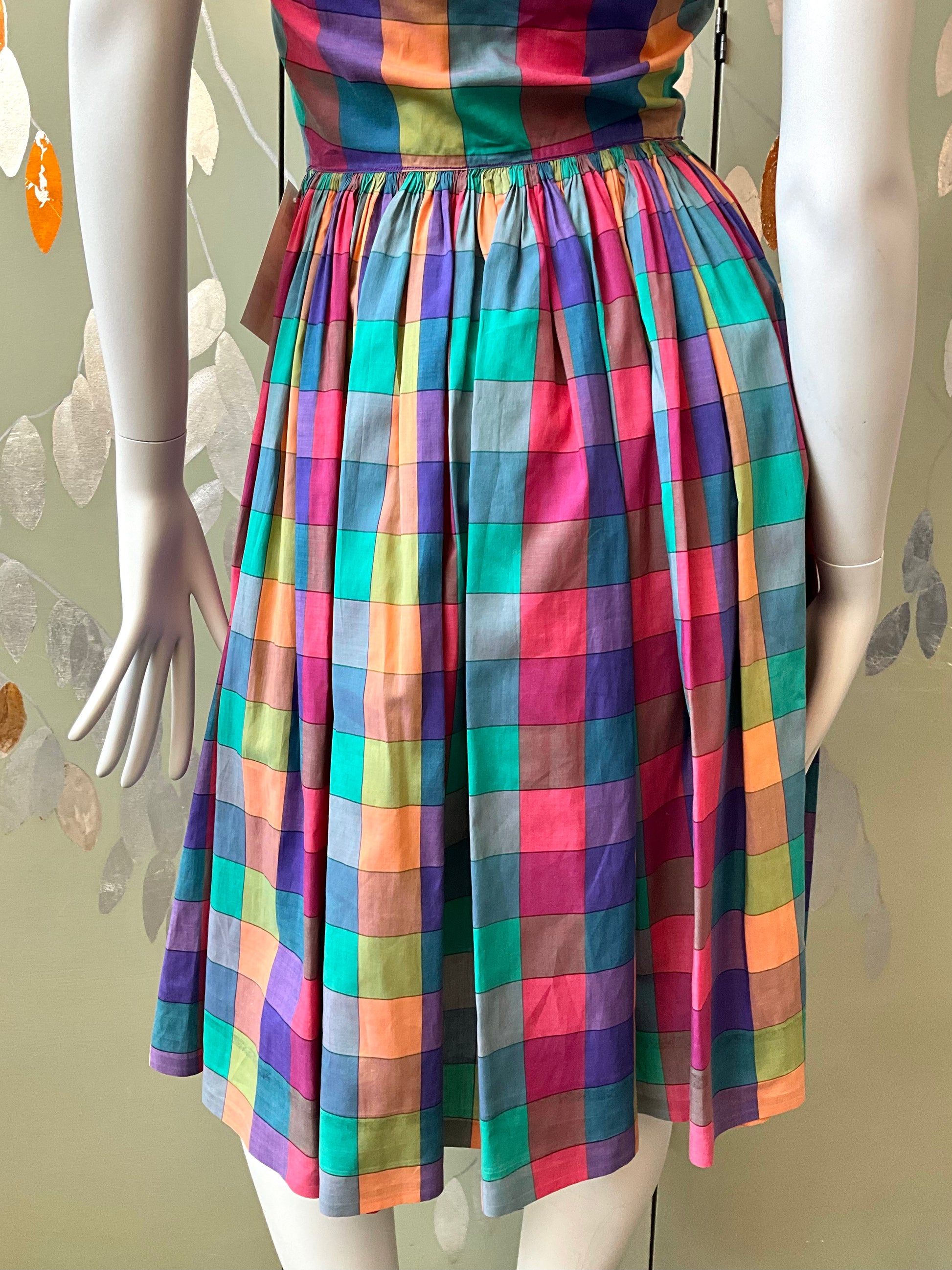 Multicolored checkered dress on a mannequin against a neutral background