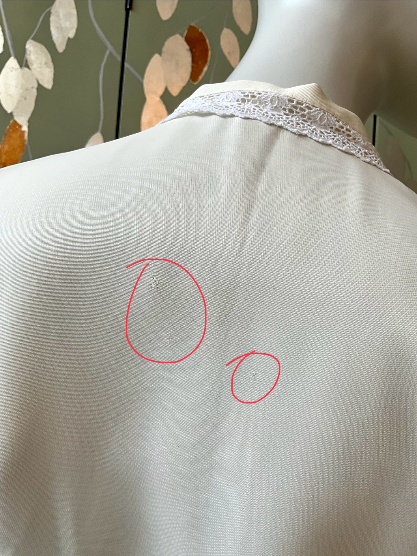 White garment with a red circle highlighting a small defect on a mannequin against a neutral background.