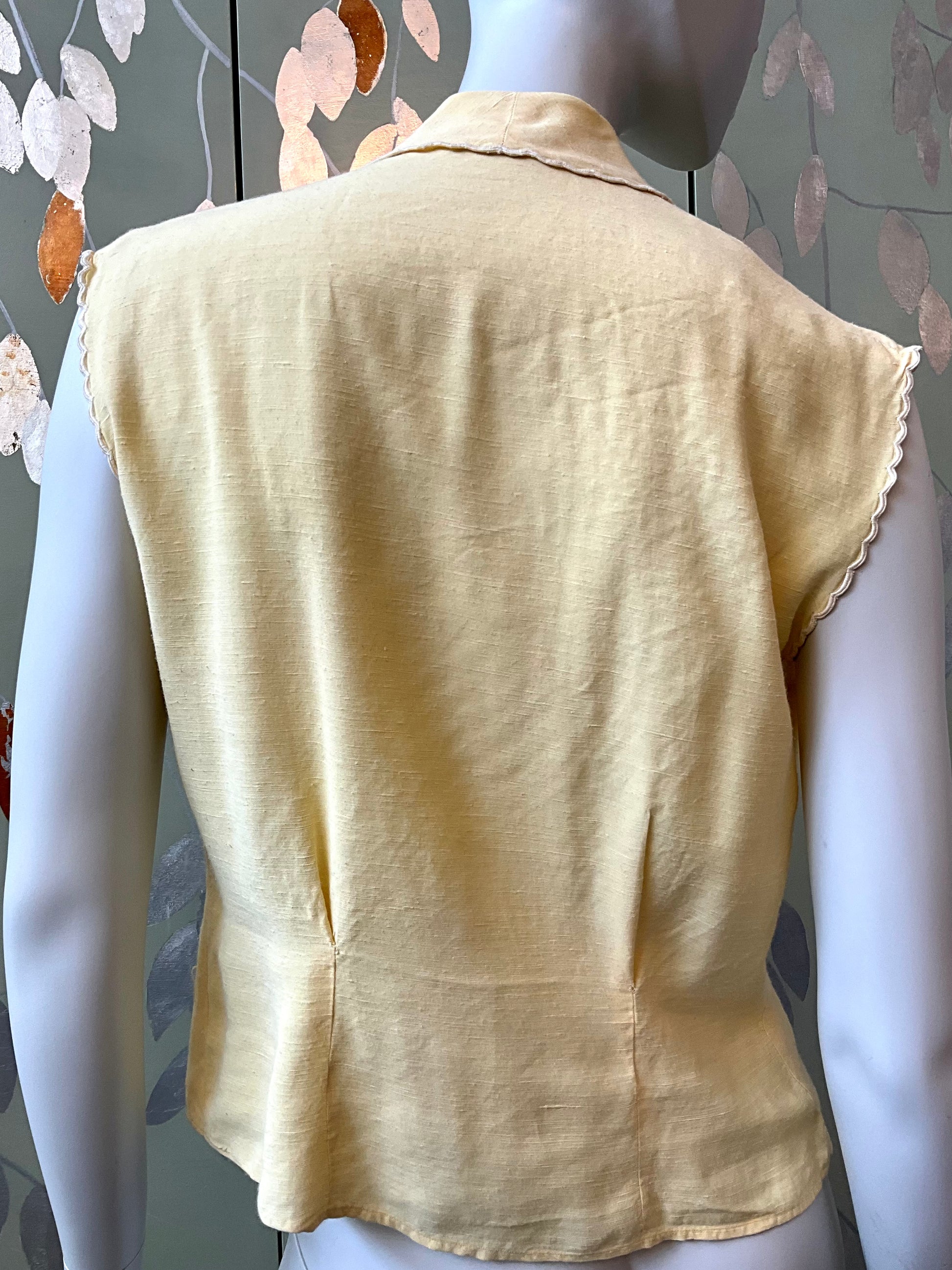 Yellow sleeveless top on a mannequin with a floral patterned background