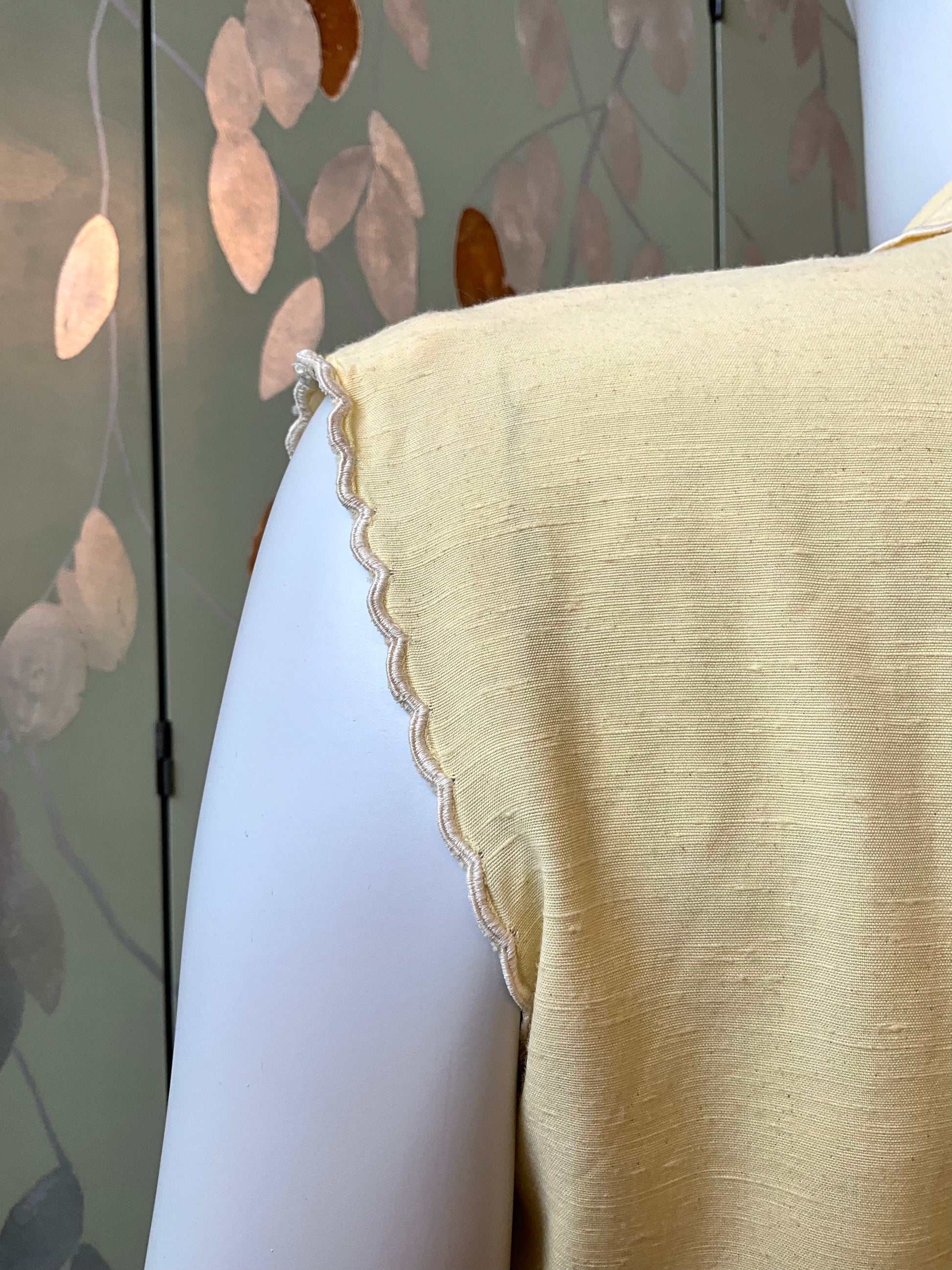 yellow blouse with scalloped edge armhole on a mannequin 