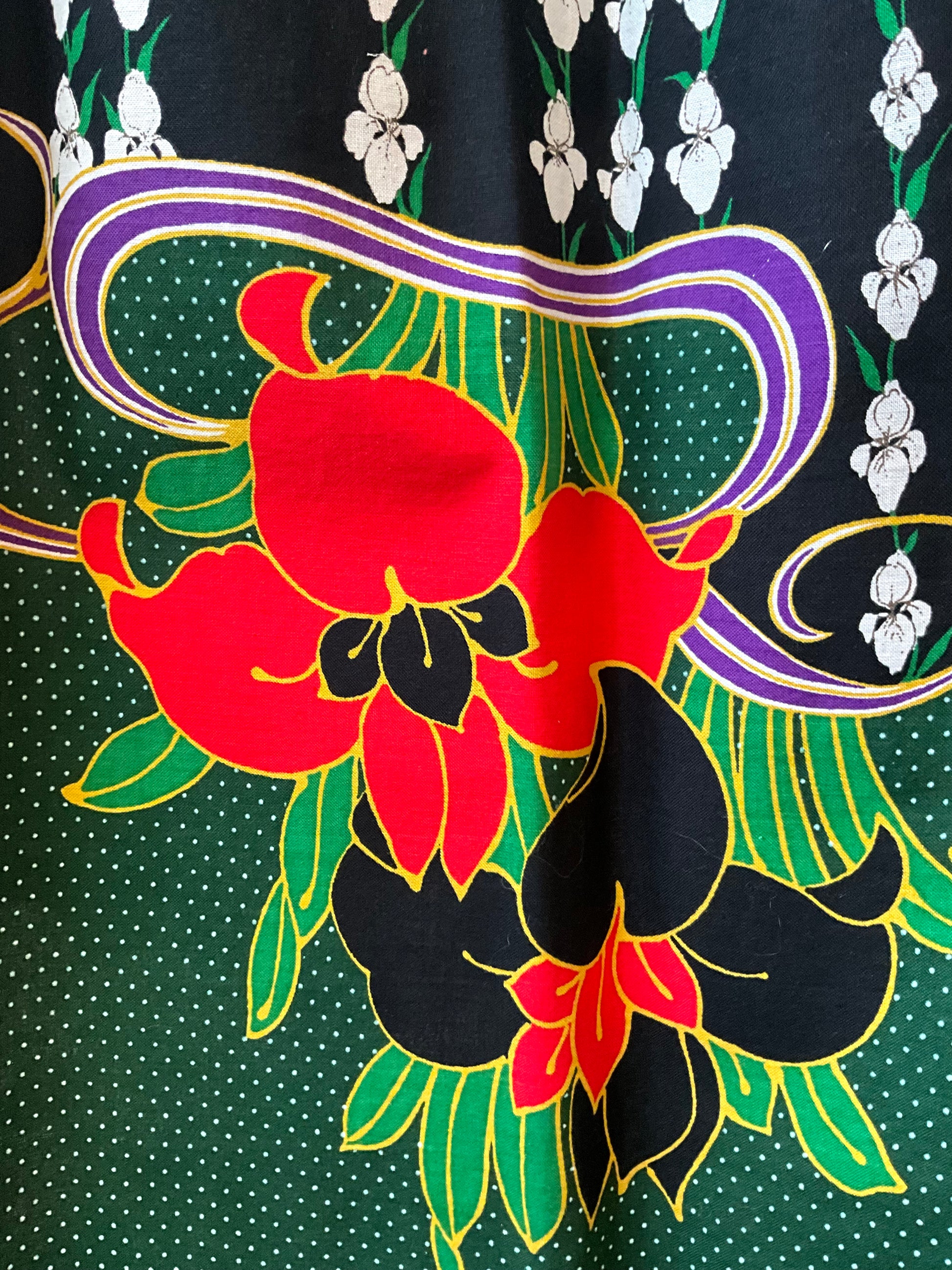 Close-up of a colorful floral pattern with red, black, and green flowers on a dark background.
