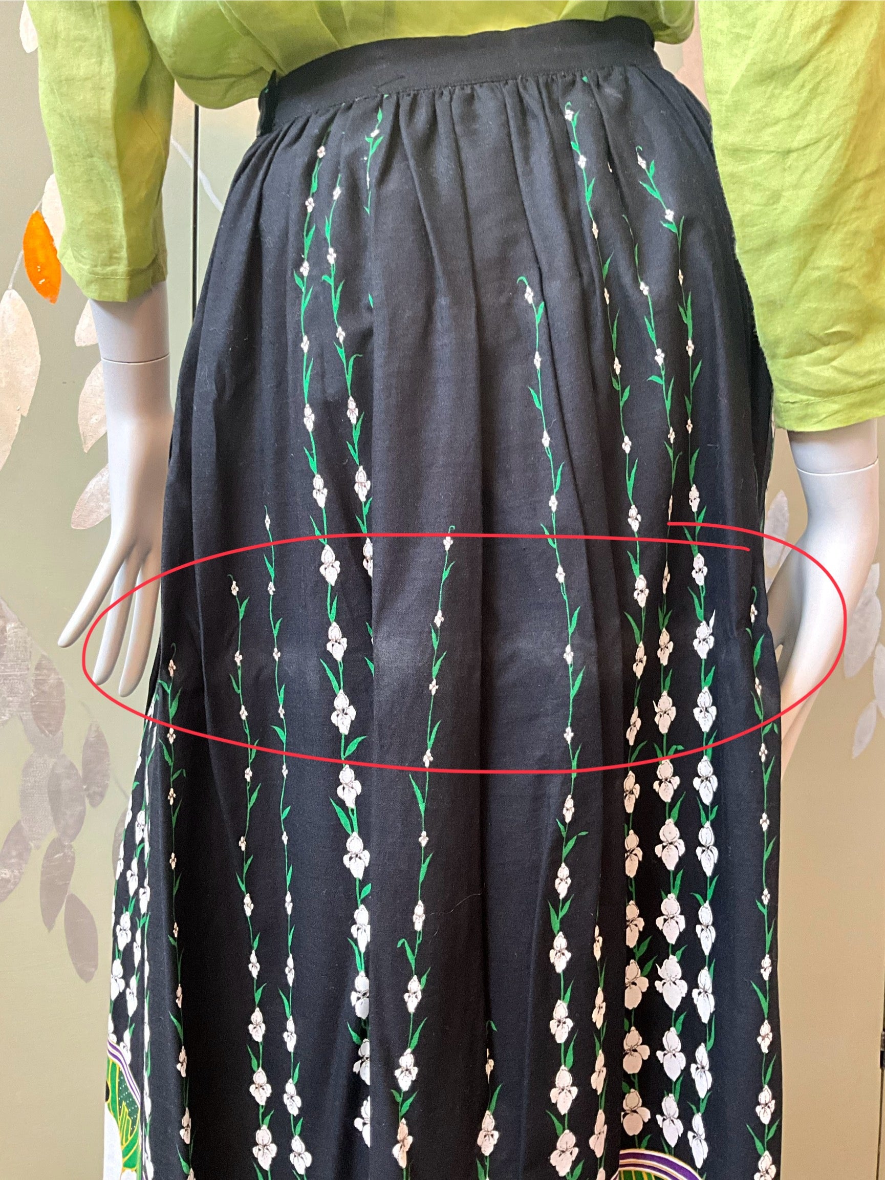 Black skirt with floral pattern on a mannequin against a neutral background