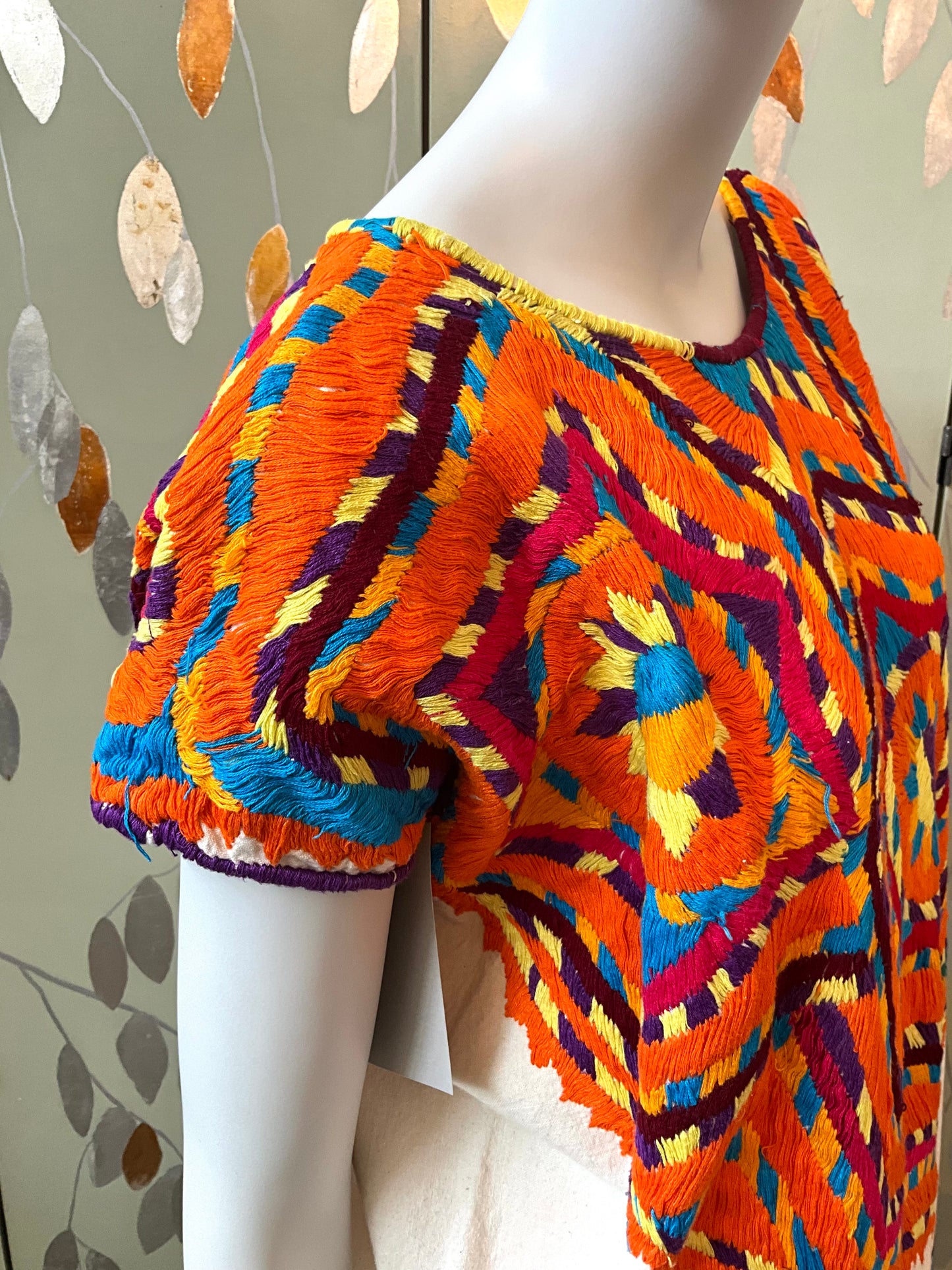 Colorful textured top on a mannequin against a neutral background