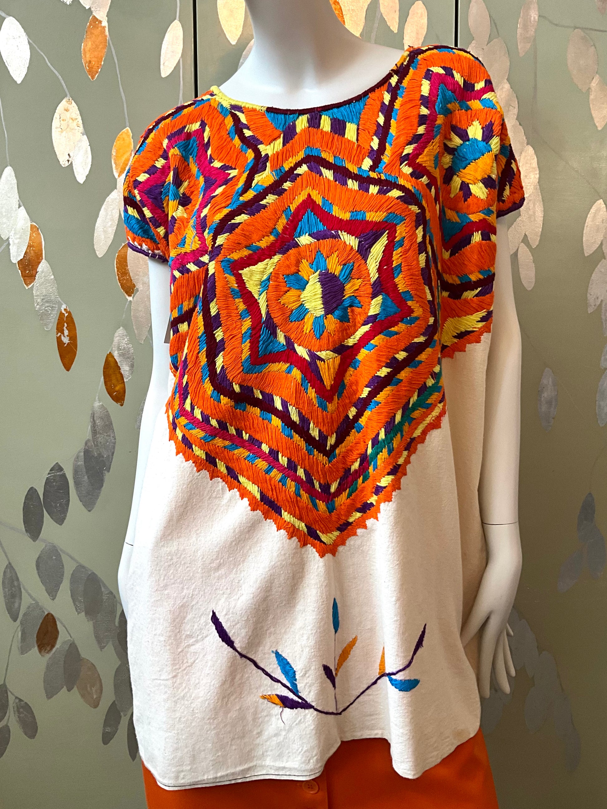Mannequin wearing a colorful patterned top with a plain background