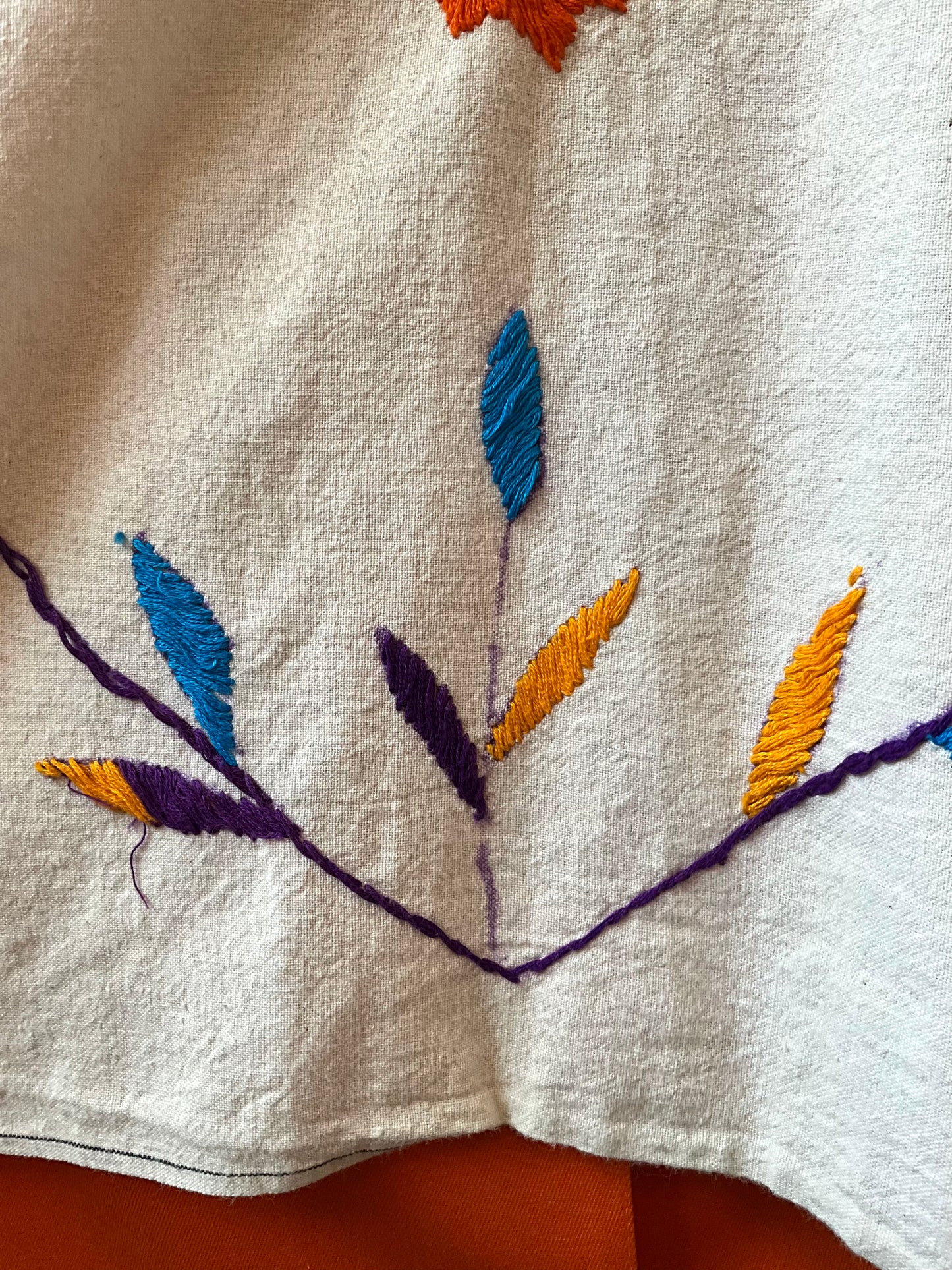 Close-up of embroidered leaves on a white fabric background