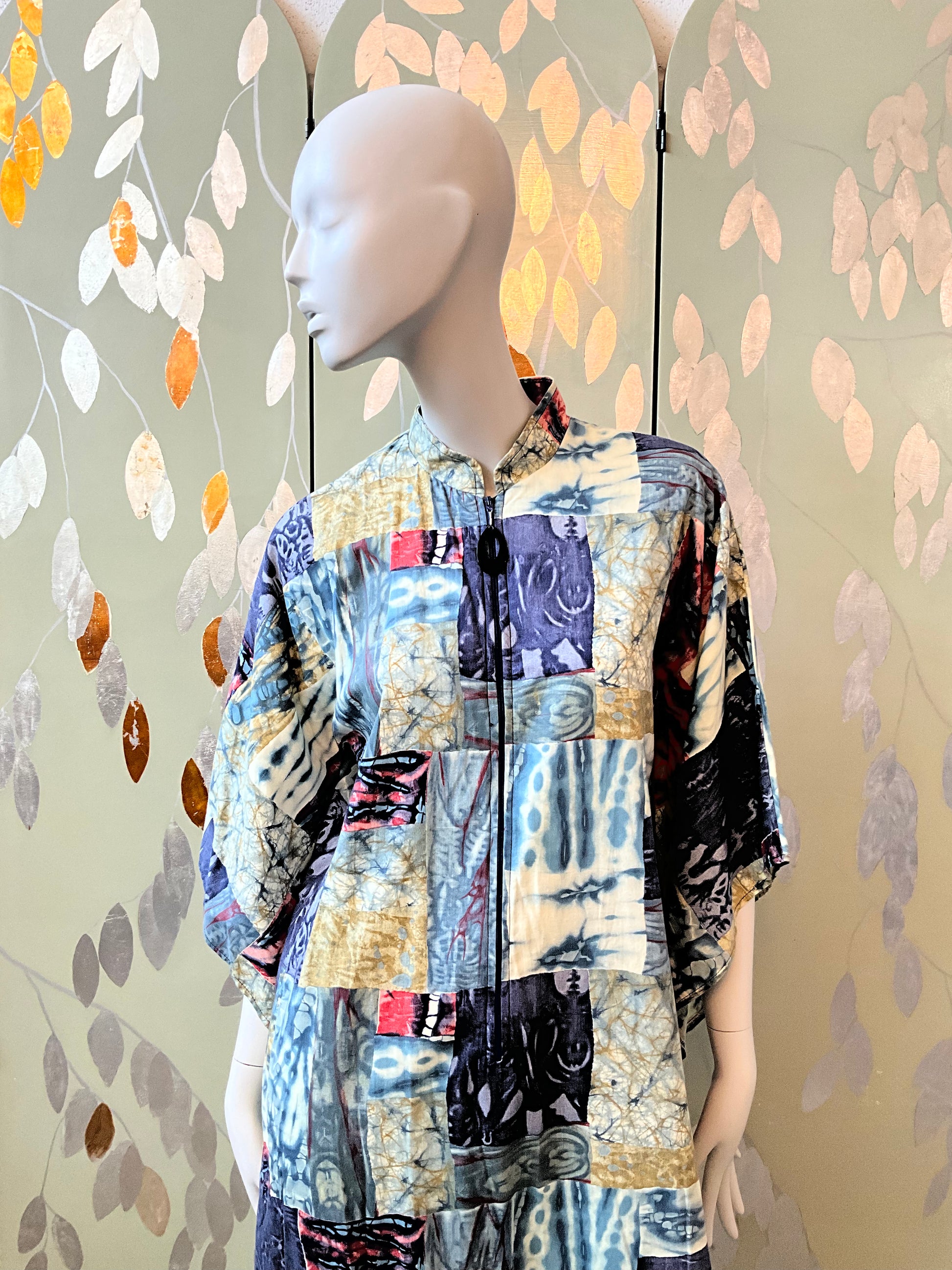 Mannequin wearing a colorful patchwork outfit against a decorative wall.
