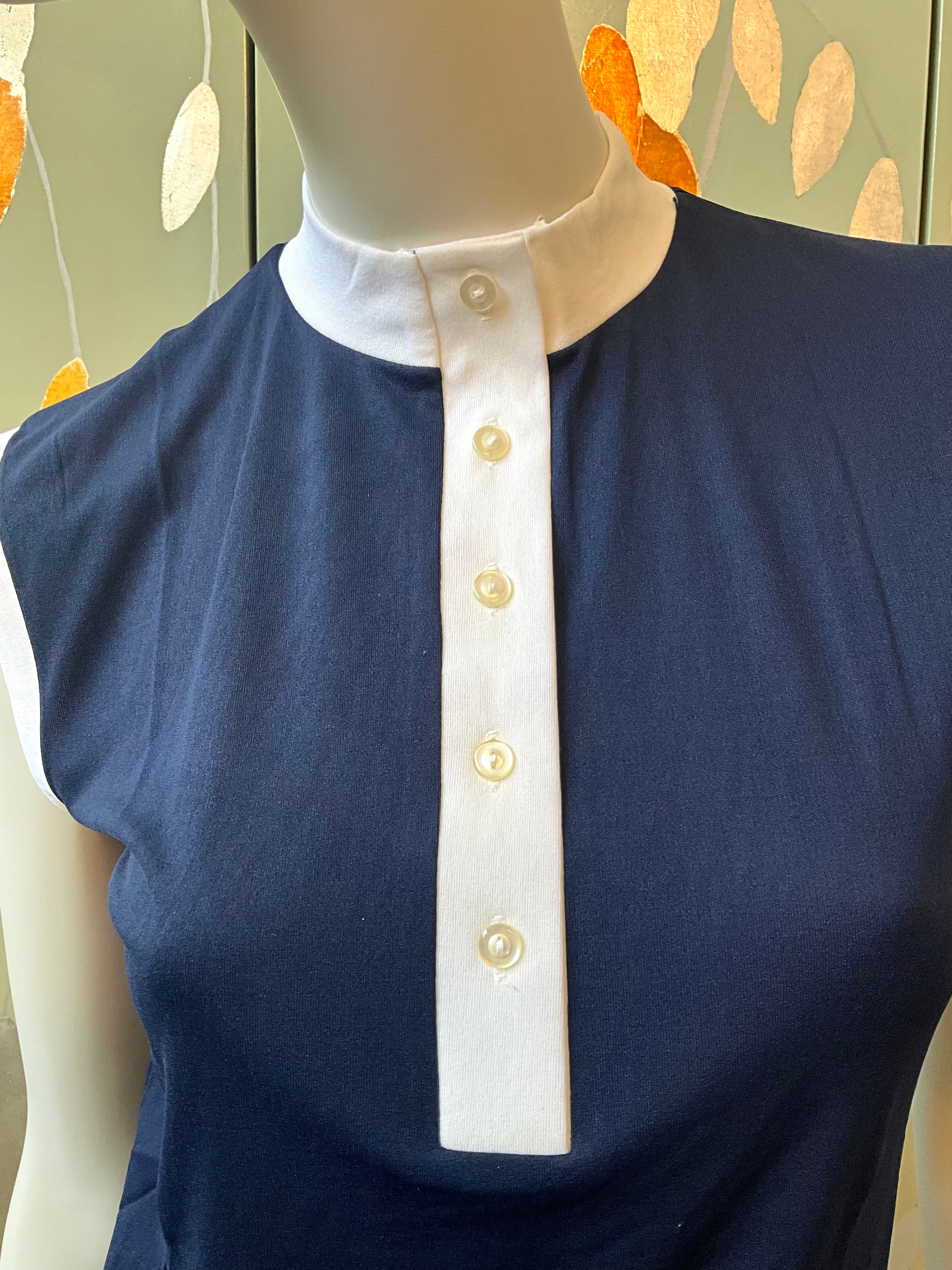 Navy blue top with white collar on a mannequin against a decorative background