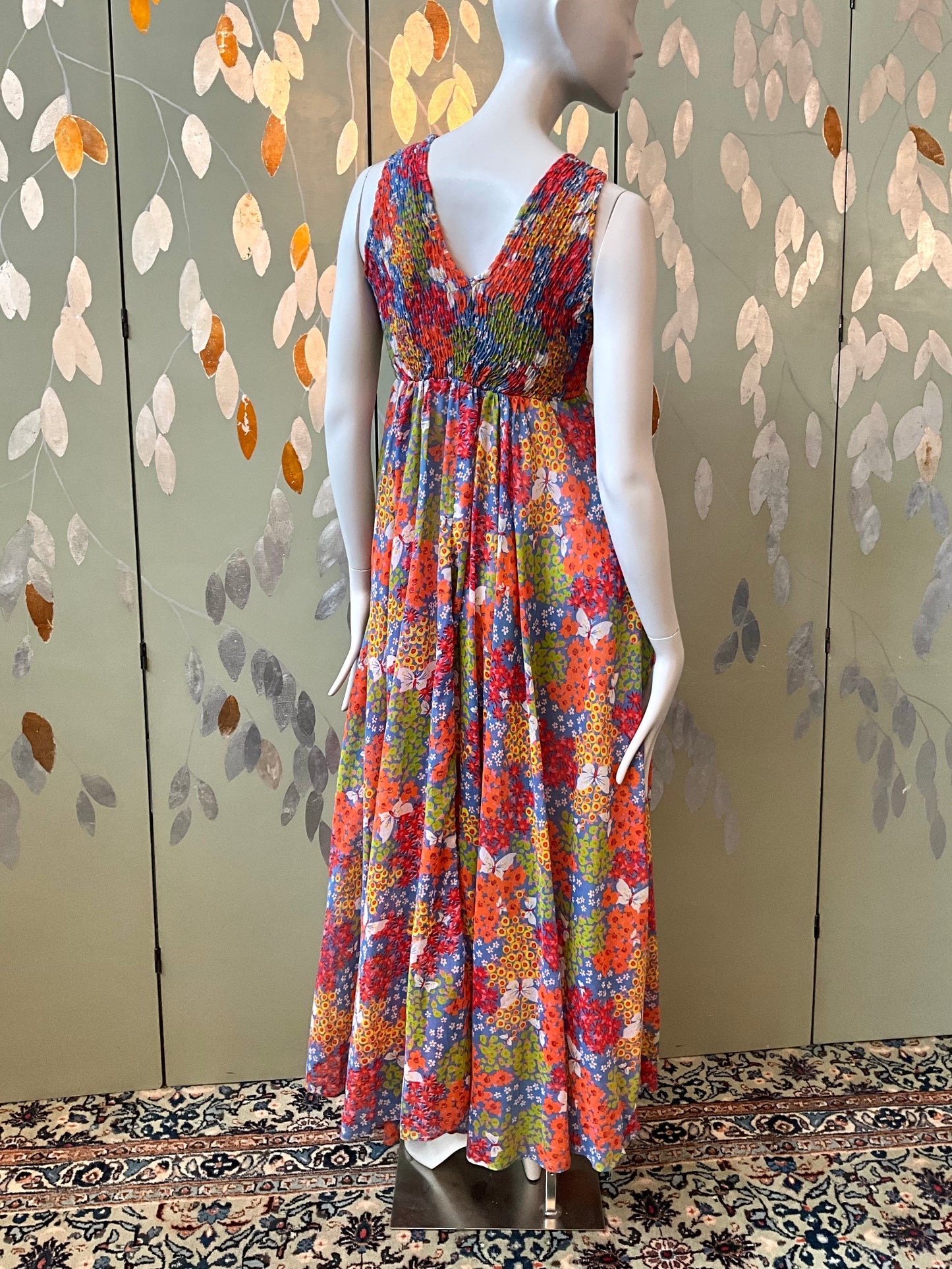 Mannequin wearing a colorful floral dress against a decorative wall.
