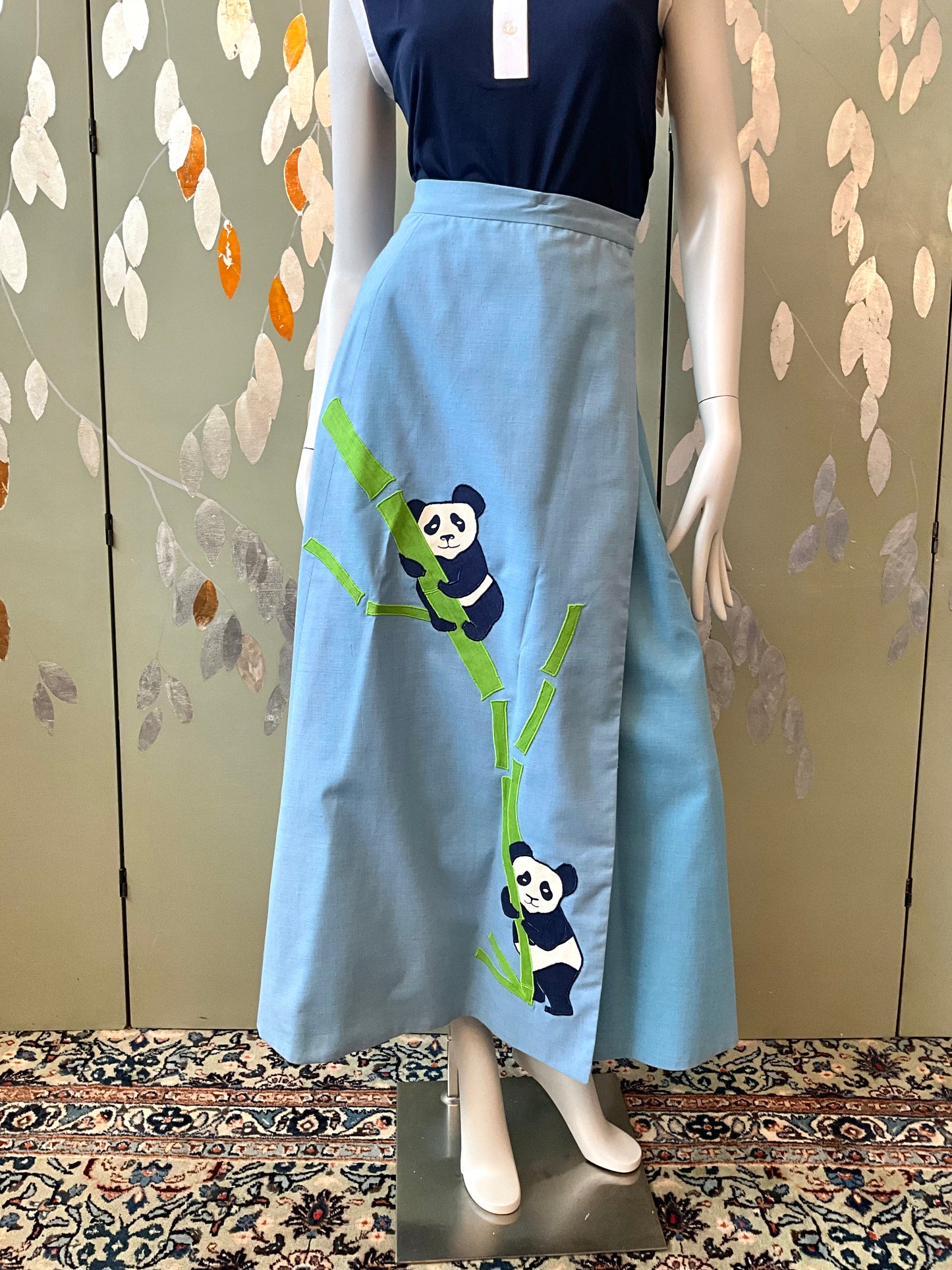 Mannequin wearing a light blue skirt with panda designs on a patterned background