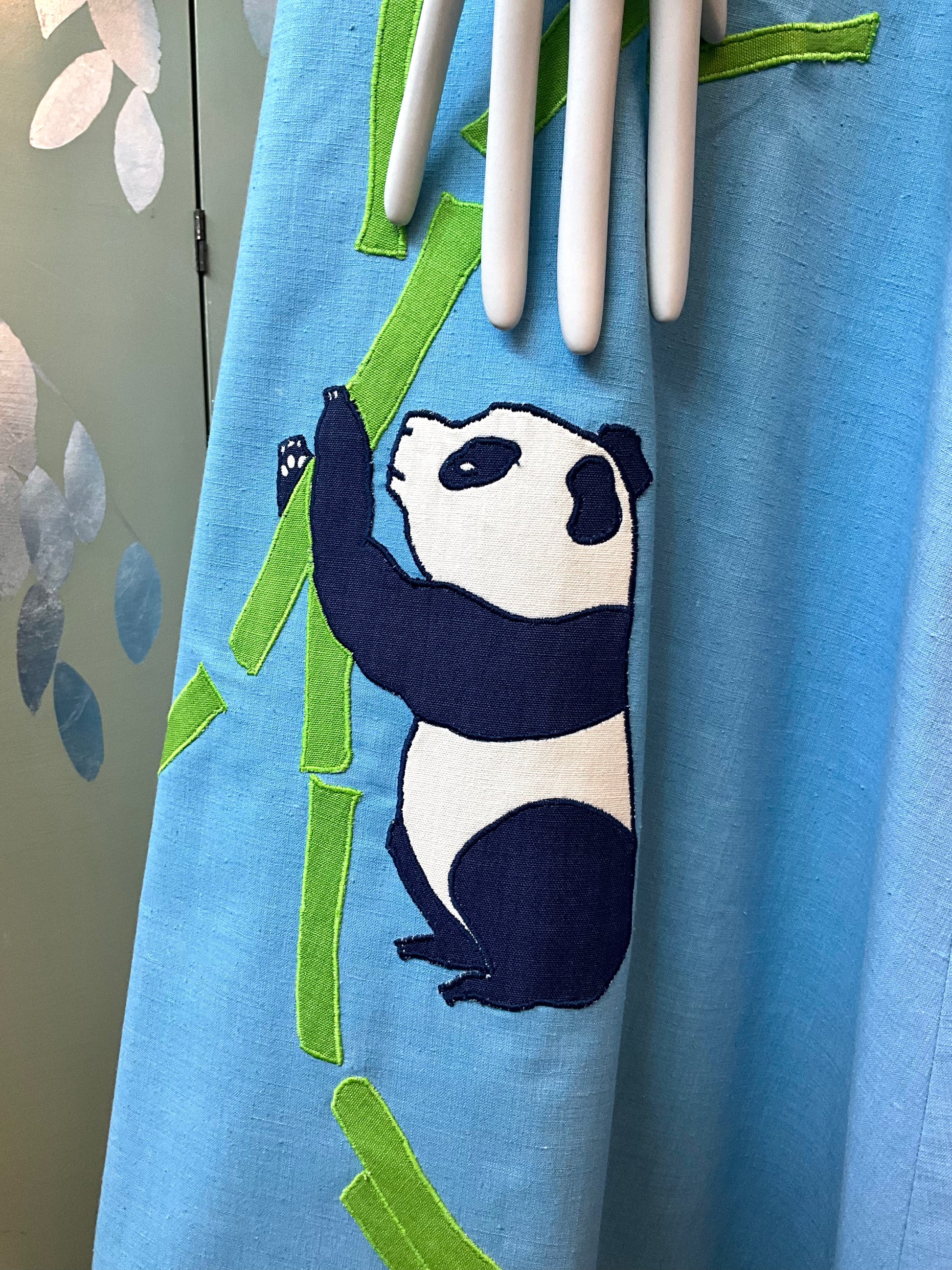 Blue fabric with a panda design and bamboo leaves on a light blue background