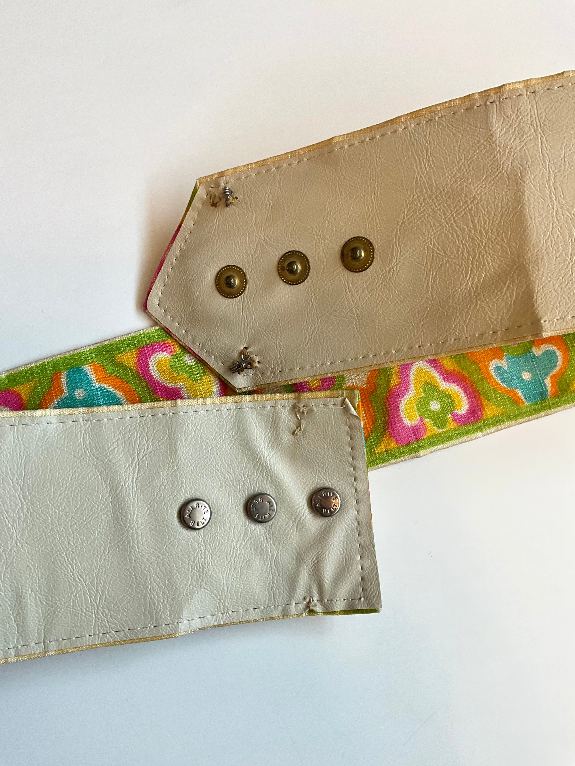 Close-up of a belt with a colorful strap and beige leather sections on a white background