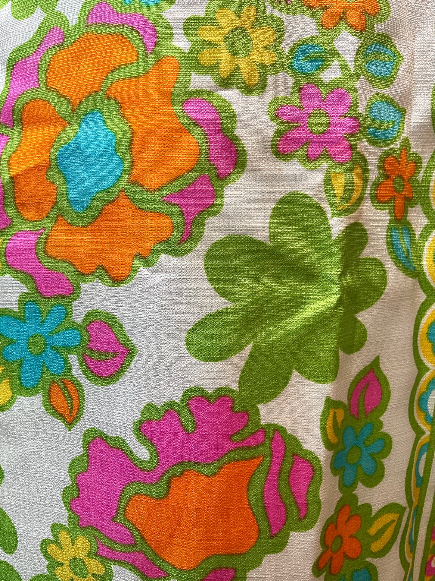 Colorful floral pattern on fabric with orange, pink, green, and blue flowers.
