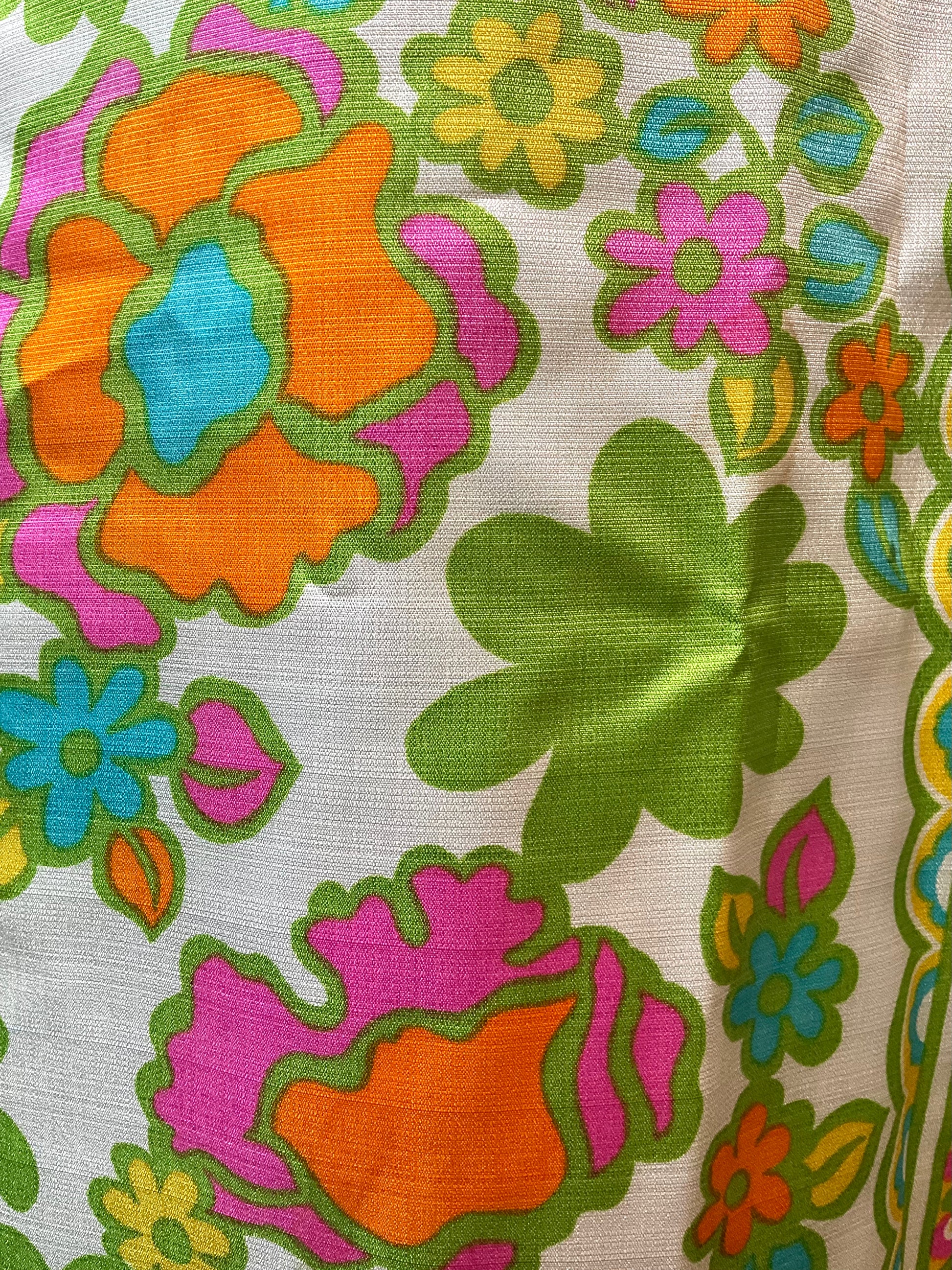 Colorful floral pattern on fabric with orange, pink, green, and blue flowers.