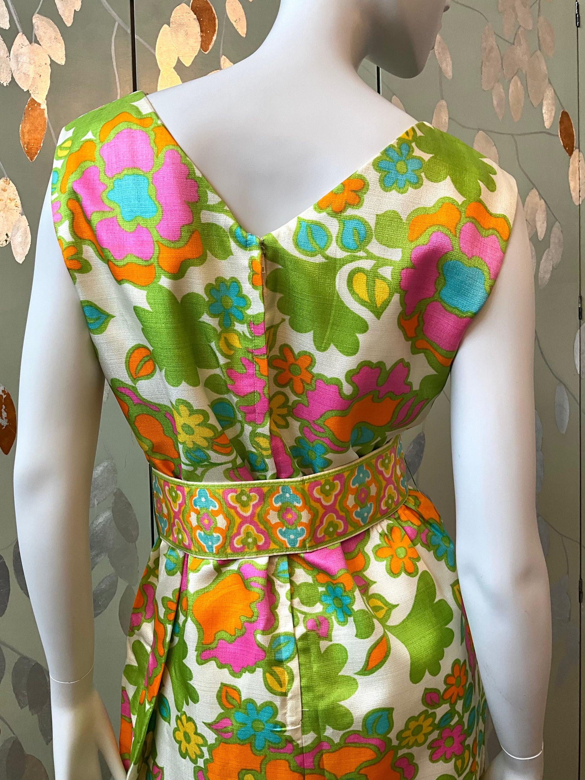 Mannequin wearing a colorful floral dress with a patterned background