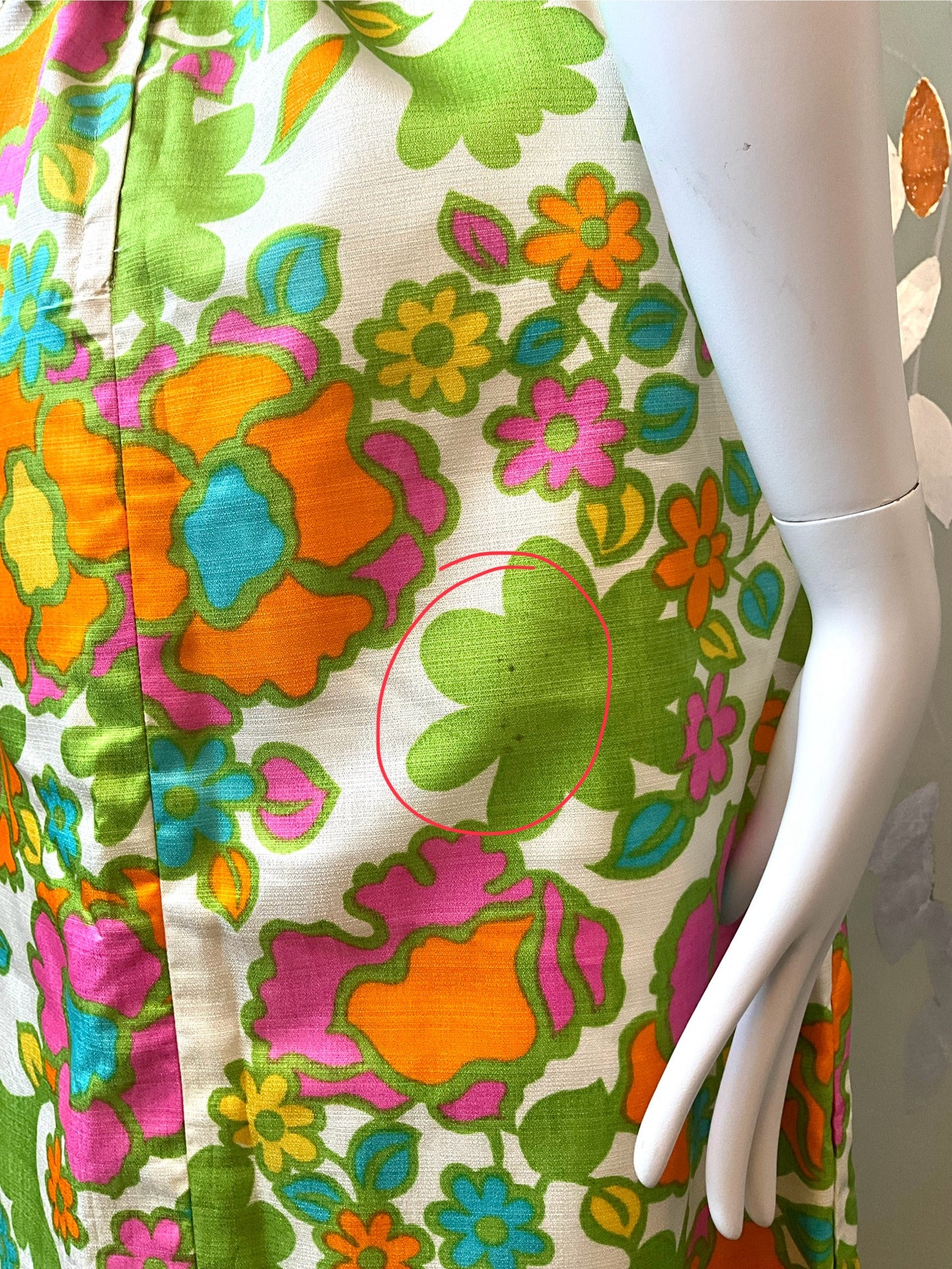 close-up of a colorful floral pattern on a dress, with a mannequin arm.