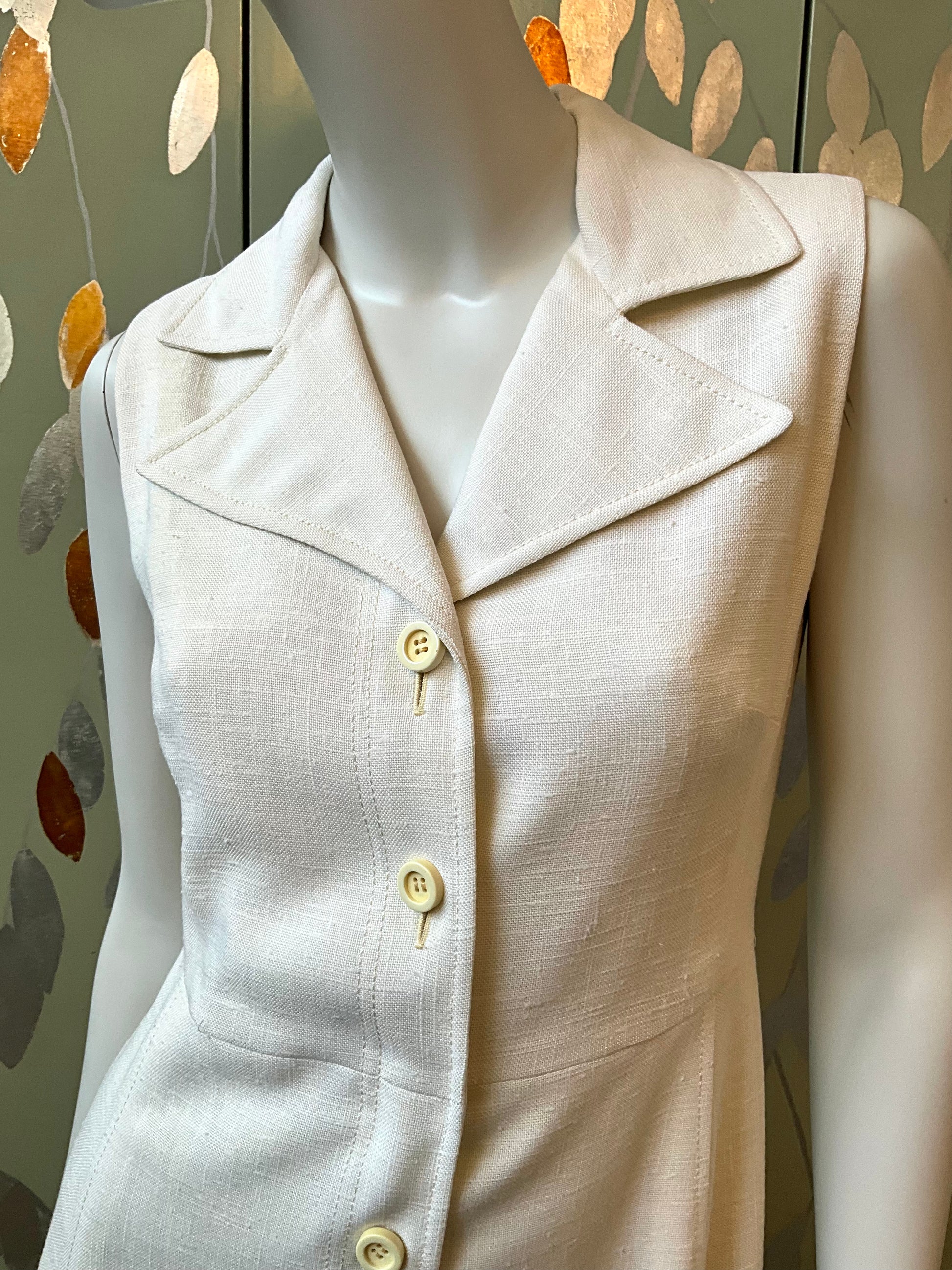 white dress on a mannequin against a decorative wall.