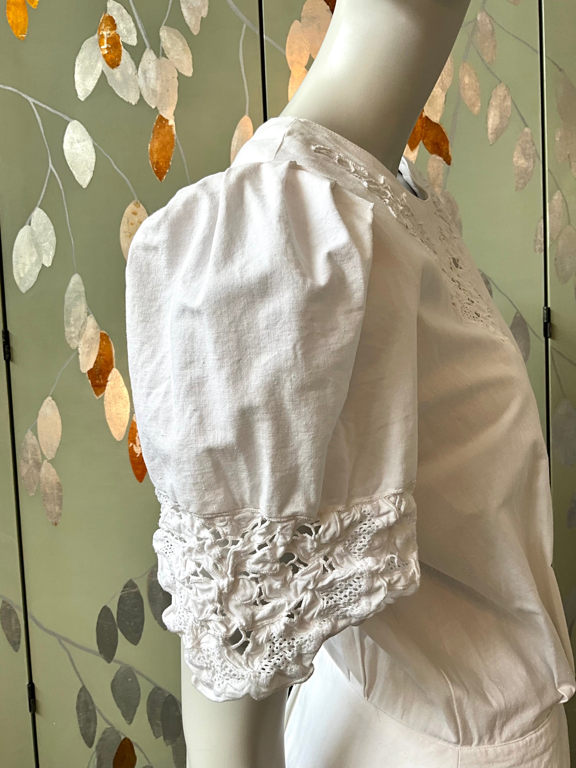 White lace dress on a mannequin against a decorative wall.