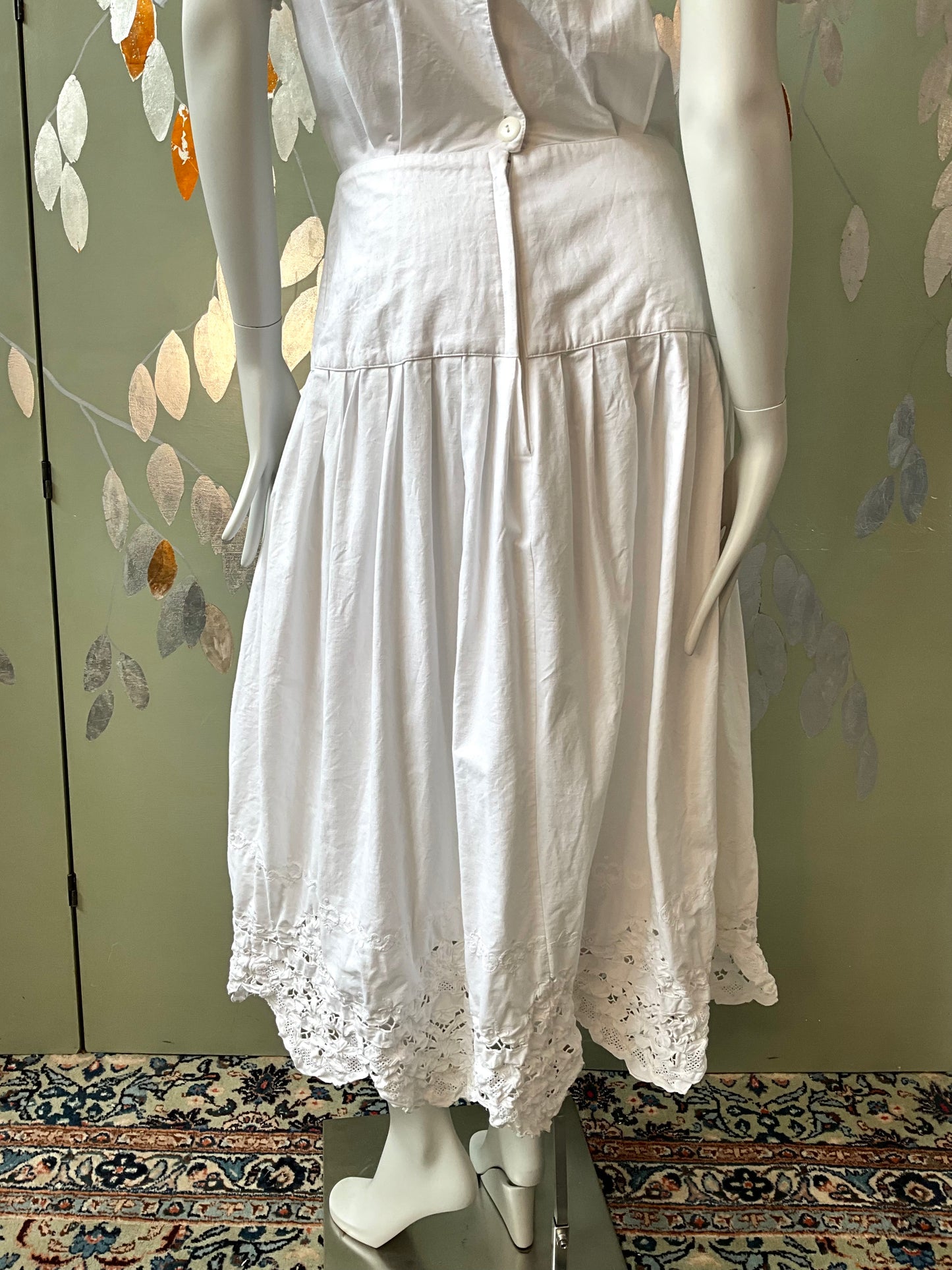 White dress on a mannequin against a floral-patterned wall.