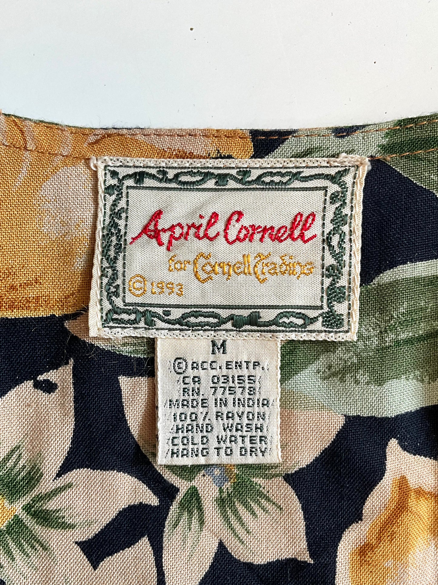 Clothing label with 'April Cornell' on a floral-patterned fabric background