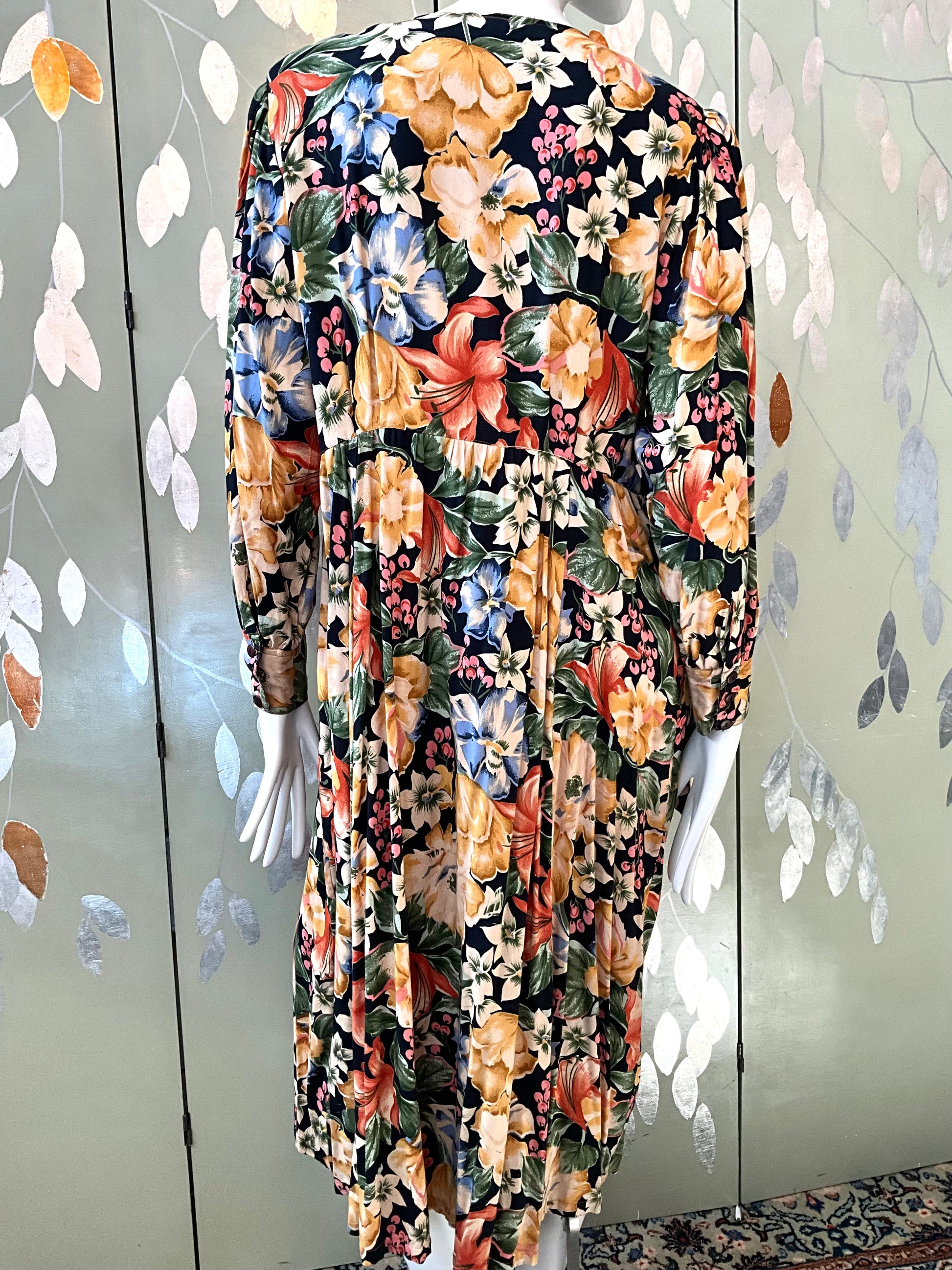 Floral patterned dress on a mannequin against a decorative wall.