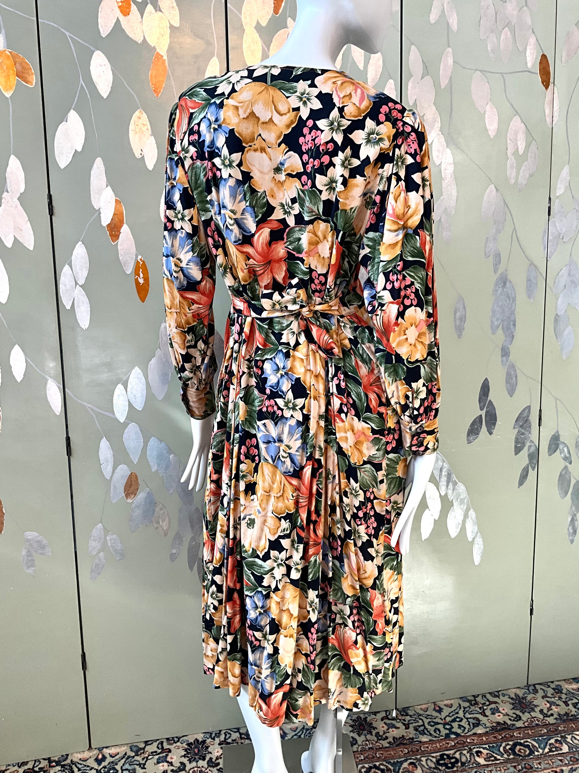 Floral dress on a mannequin against a decorative wall.