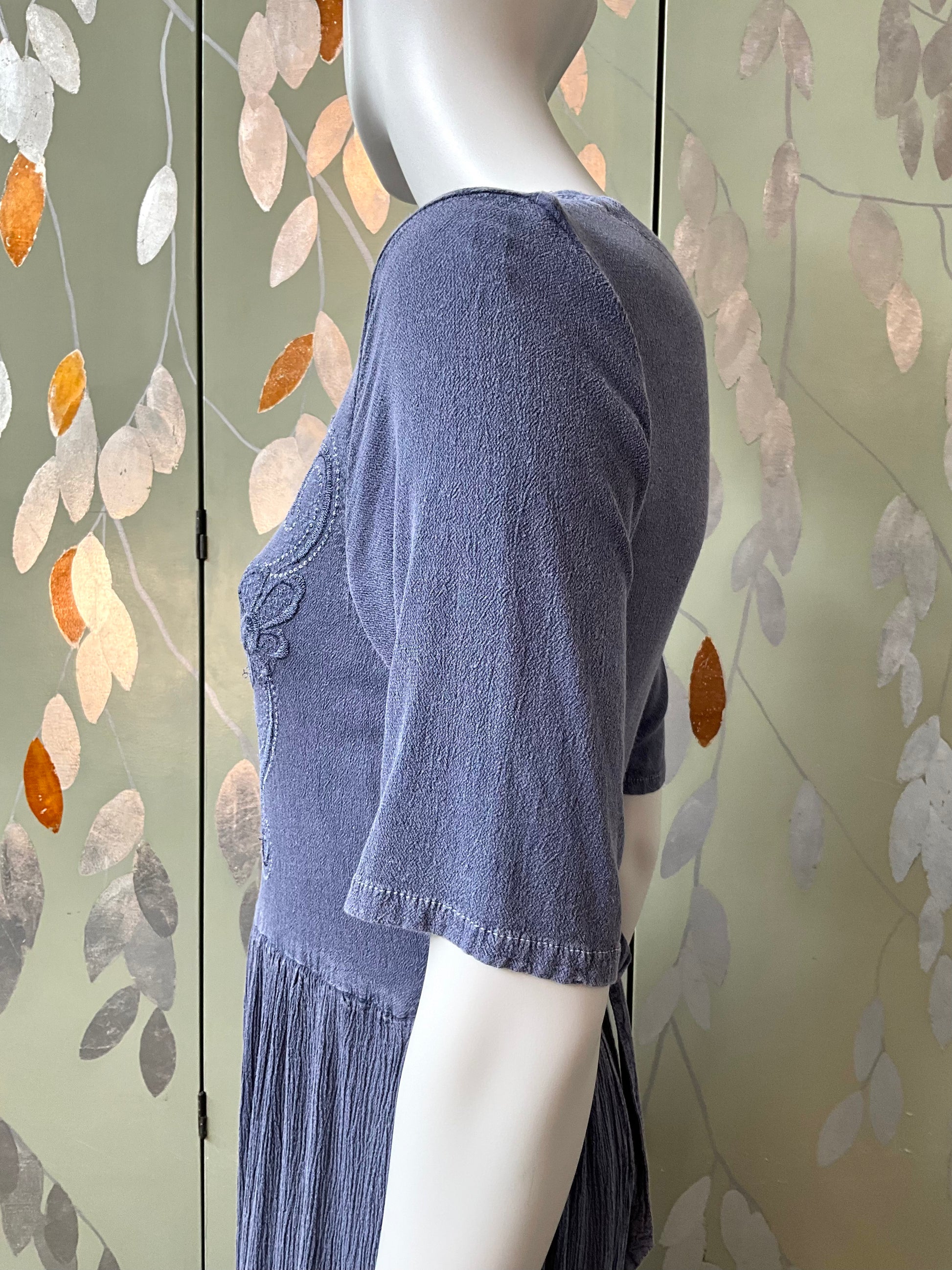 Mannequin wearing a blue dress with a floral background