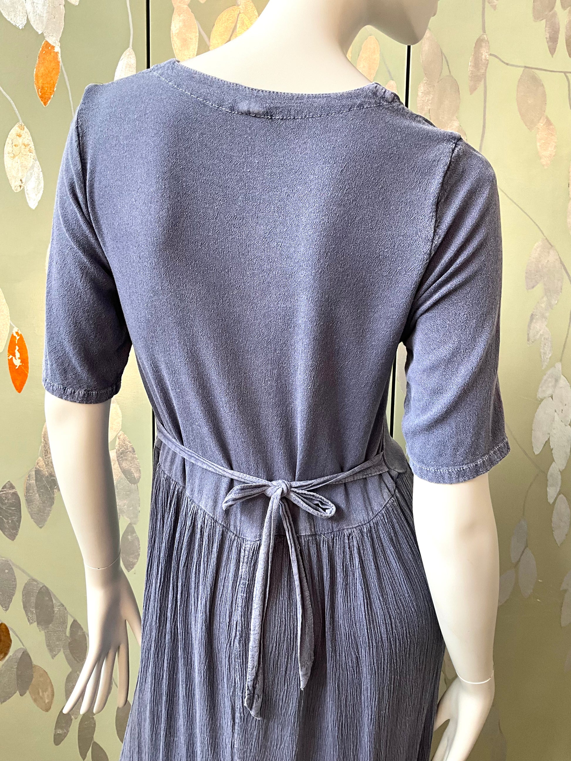 Mannequin wearing a blue dress with a patterned background