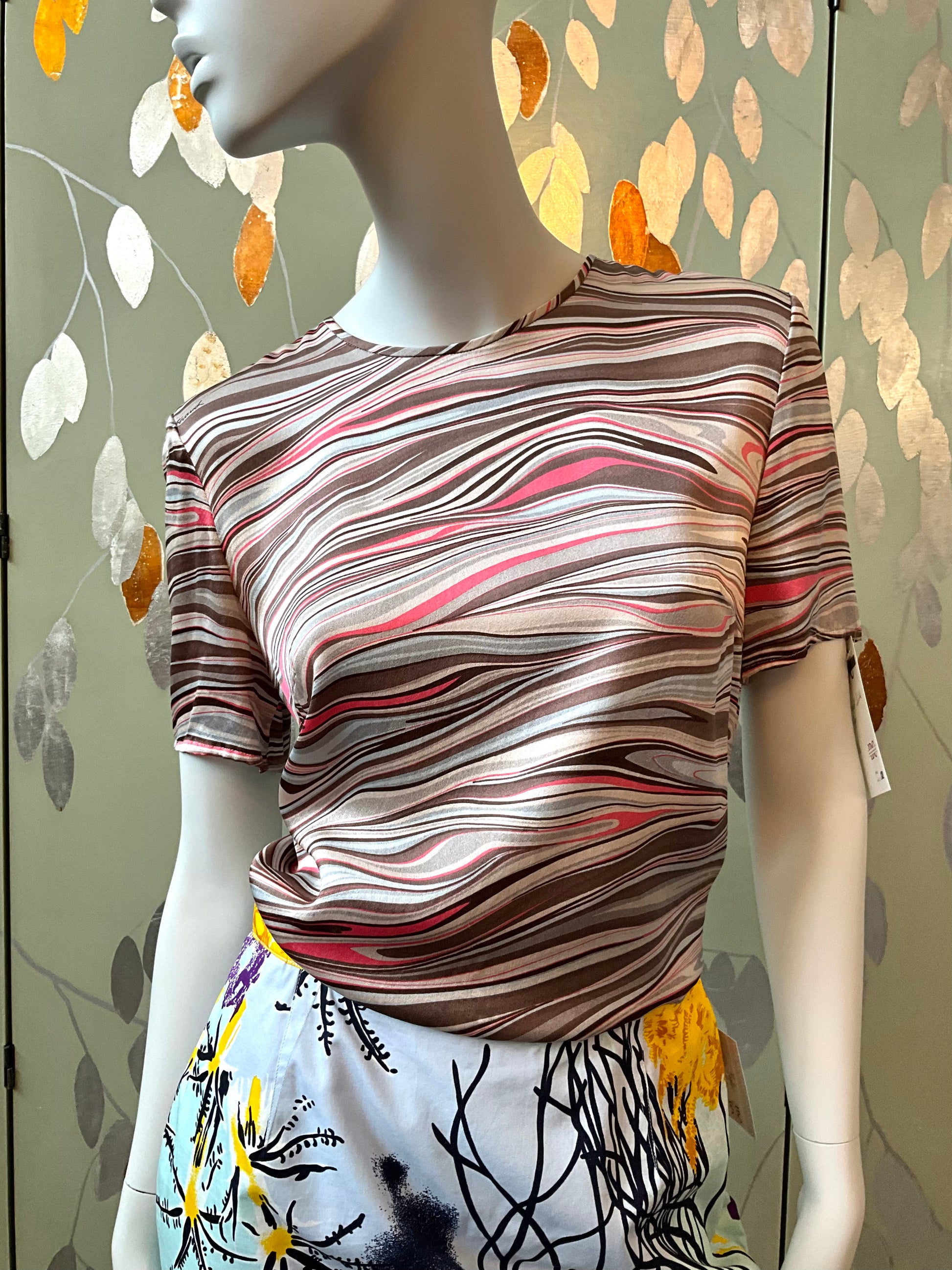 Mannequin wearing a patterned top with a colorful leafy background
